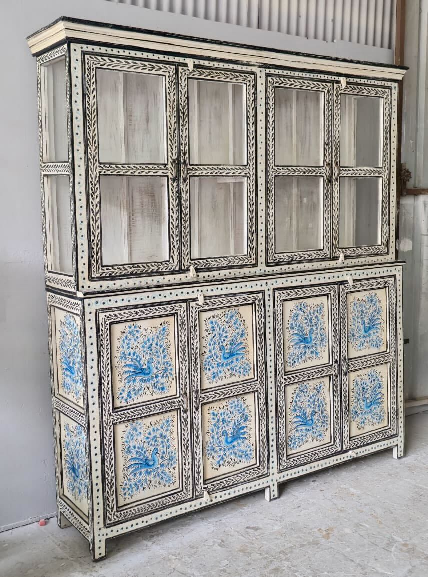 Side angle image of a hand-painted reclaimed wood display cabinet with glass doors and floral blue peacock design – Aadrika model by Om Home & Garden