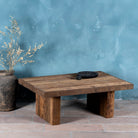 Front view of a rectangular rustic coffee table constructed from reclaimed wood, featuring a thick plank-style top and wide block legs, all with a naturally weathered finish that highlights the wood’s grain and imperfections.