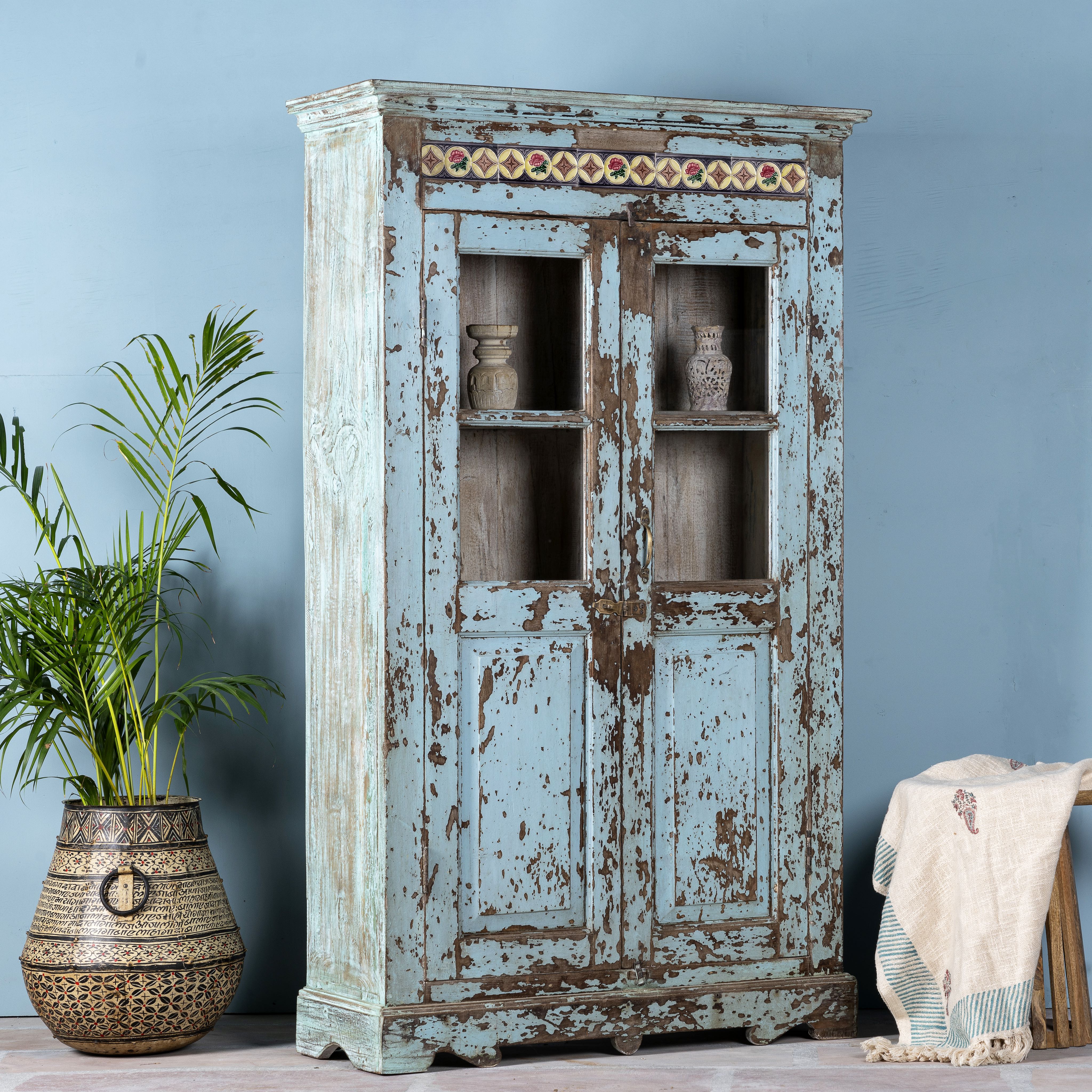 Side angle image of a reclaimed teak wood display cabinet with light blue shabby chic finish and ceramic inlays – sustainable teak wood showcase with glass doors.