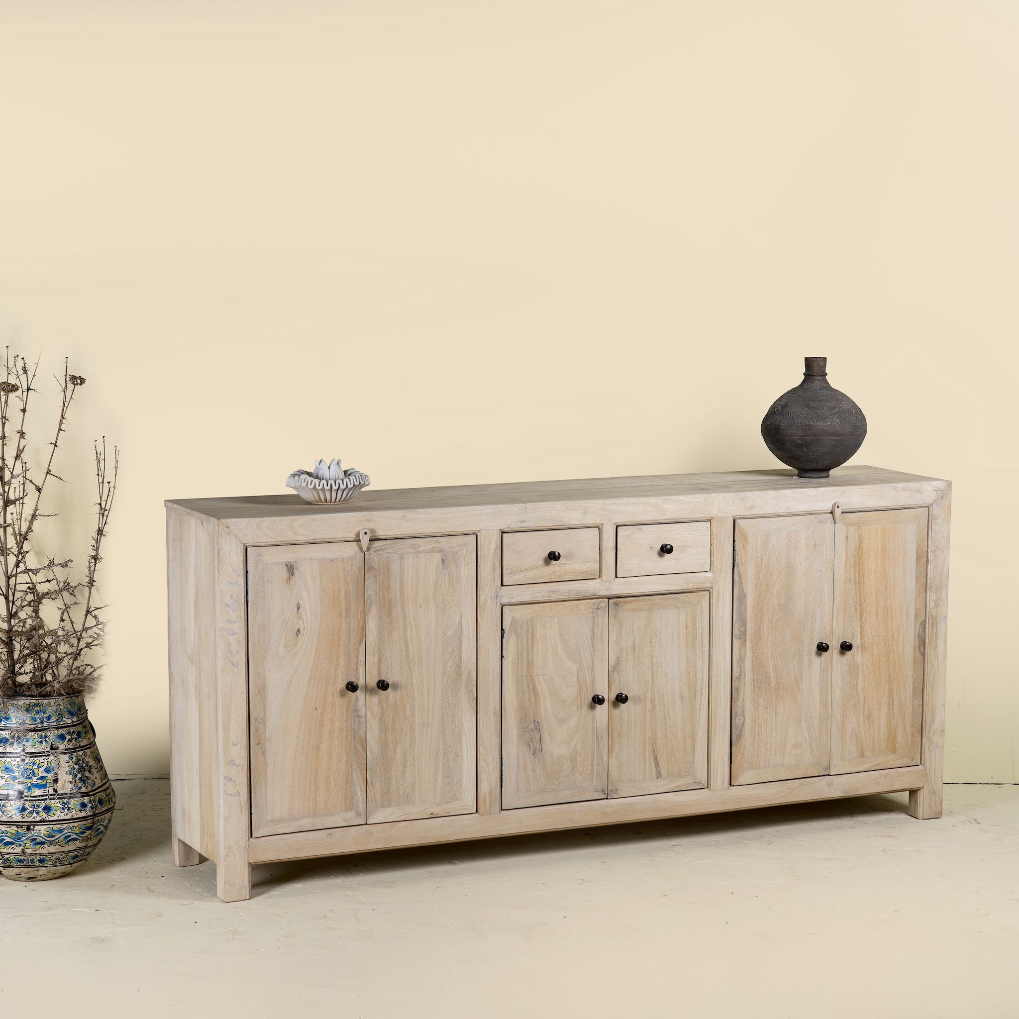 Side angle image of a sandblasted wooden sideboard with three compartments and two small drawers, Ibiza style living room furniture in light natural finish, 200×40×90 cm.