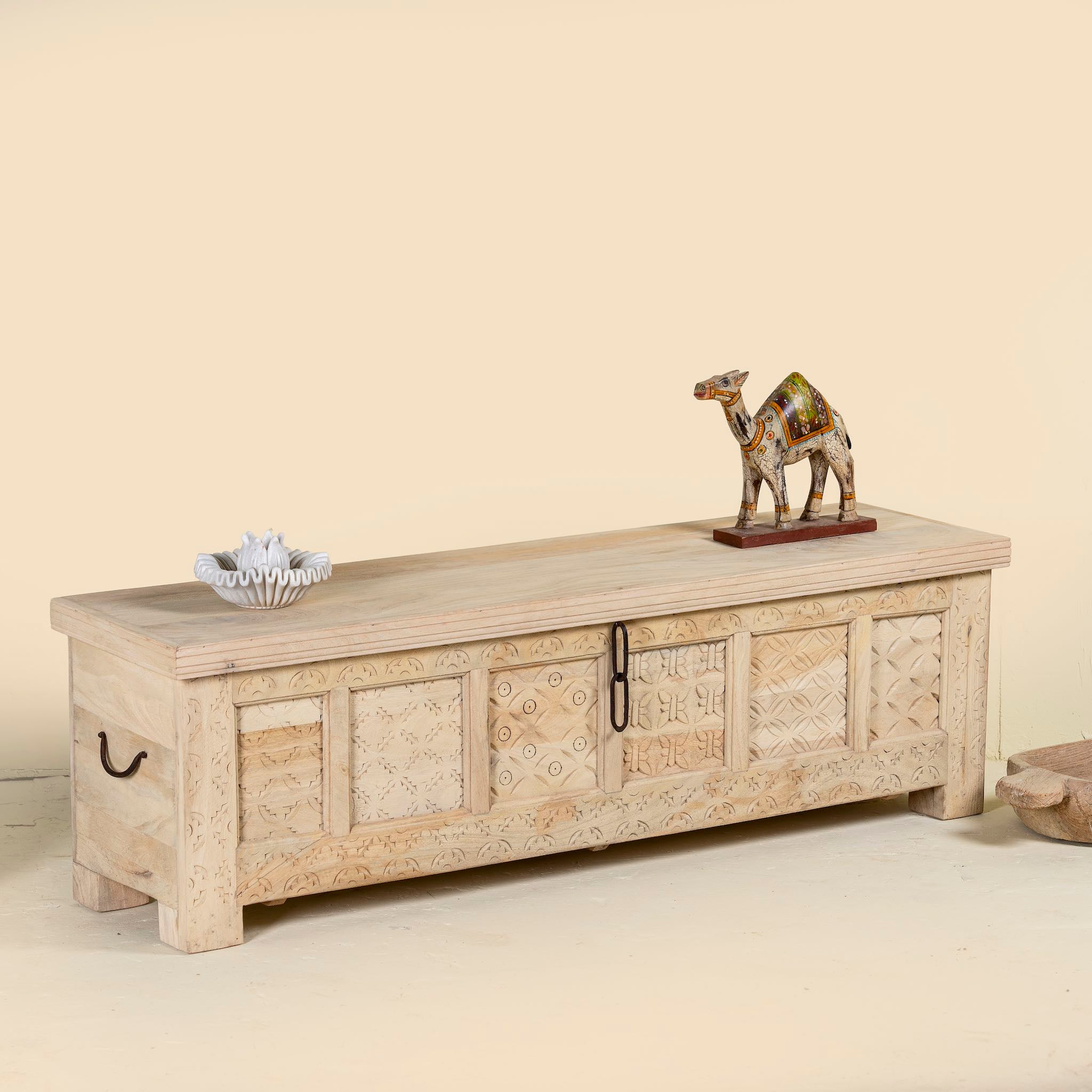 Side angle image of a Ibiza style carved mango wood chest with sandblasted finish and iron lock; 150 × 40 × 45 cm.