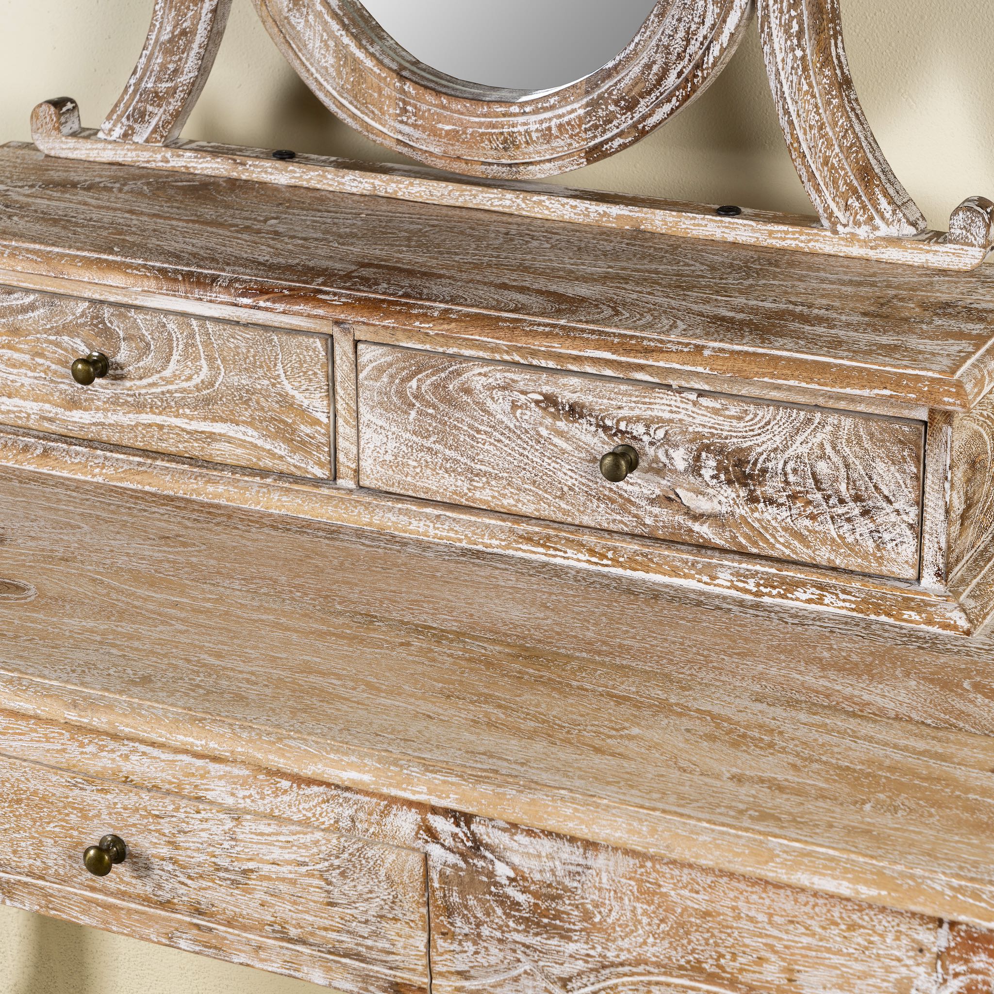 Close up image of a handcrafted mango wood cosmetic table with a curved mirror and matching stool, showcasing a vintage style with a beige finish.
