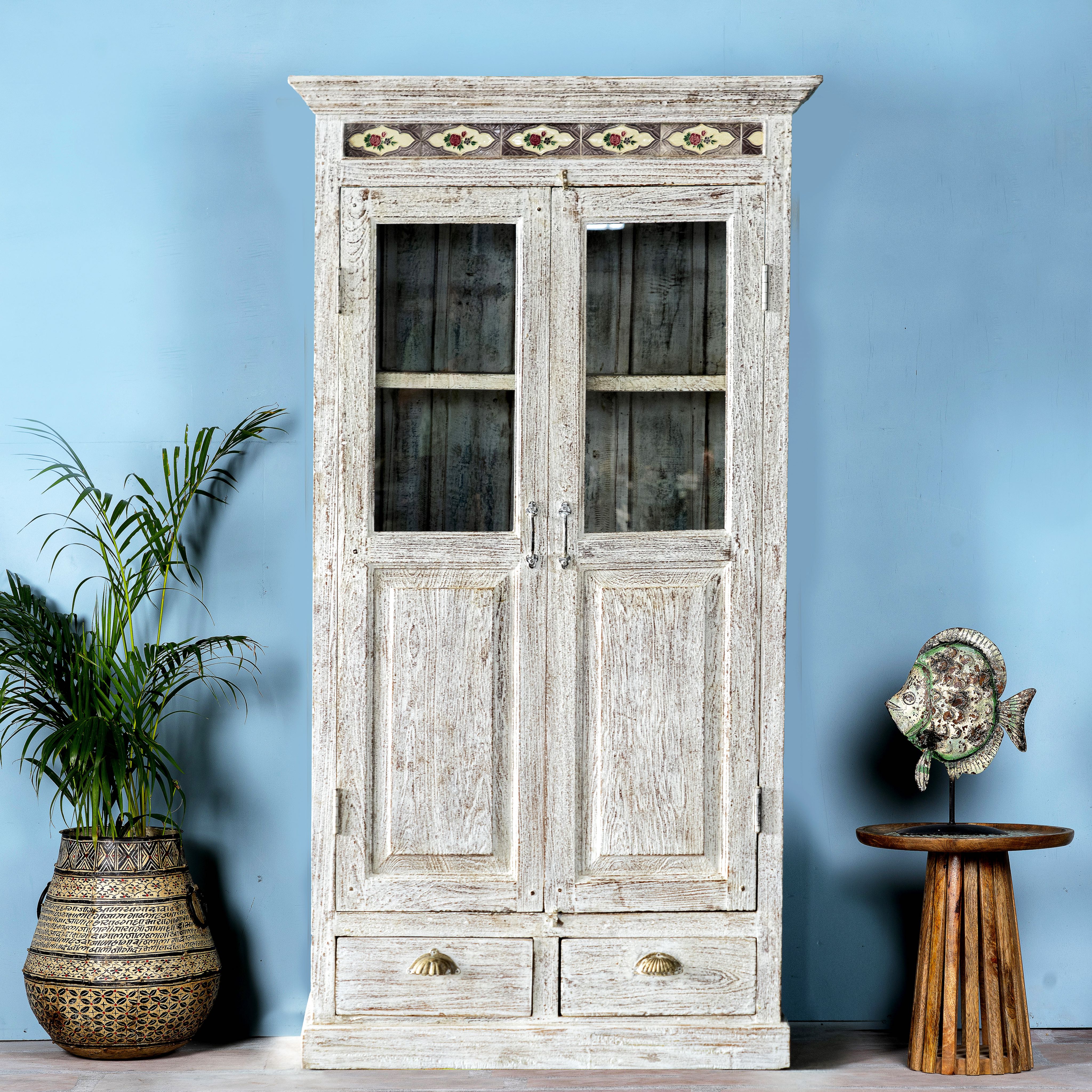A refurbished antique teak wood showcase with ceramics. The showcase has a shabby chic white finish, features glass doors, and is adorned with Portuguese ceramic inlays.