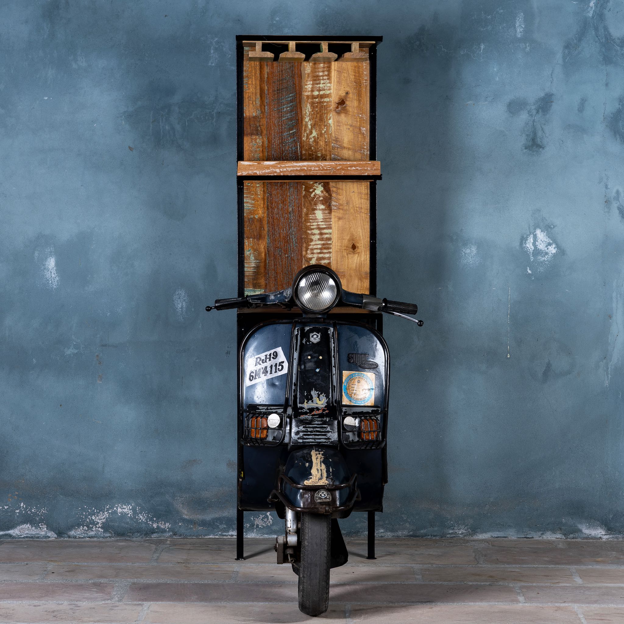 Front image of a high bar table featuring the front half of a vintage Bajaj scooter, with tall wooden shelving and an industrial metal frame, designed for stylish bar storage.