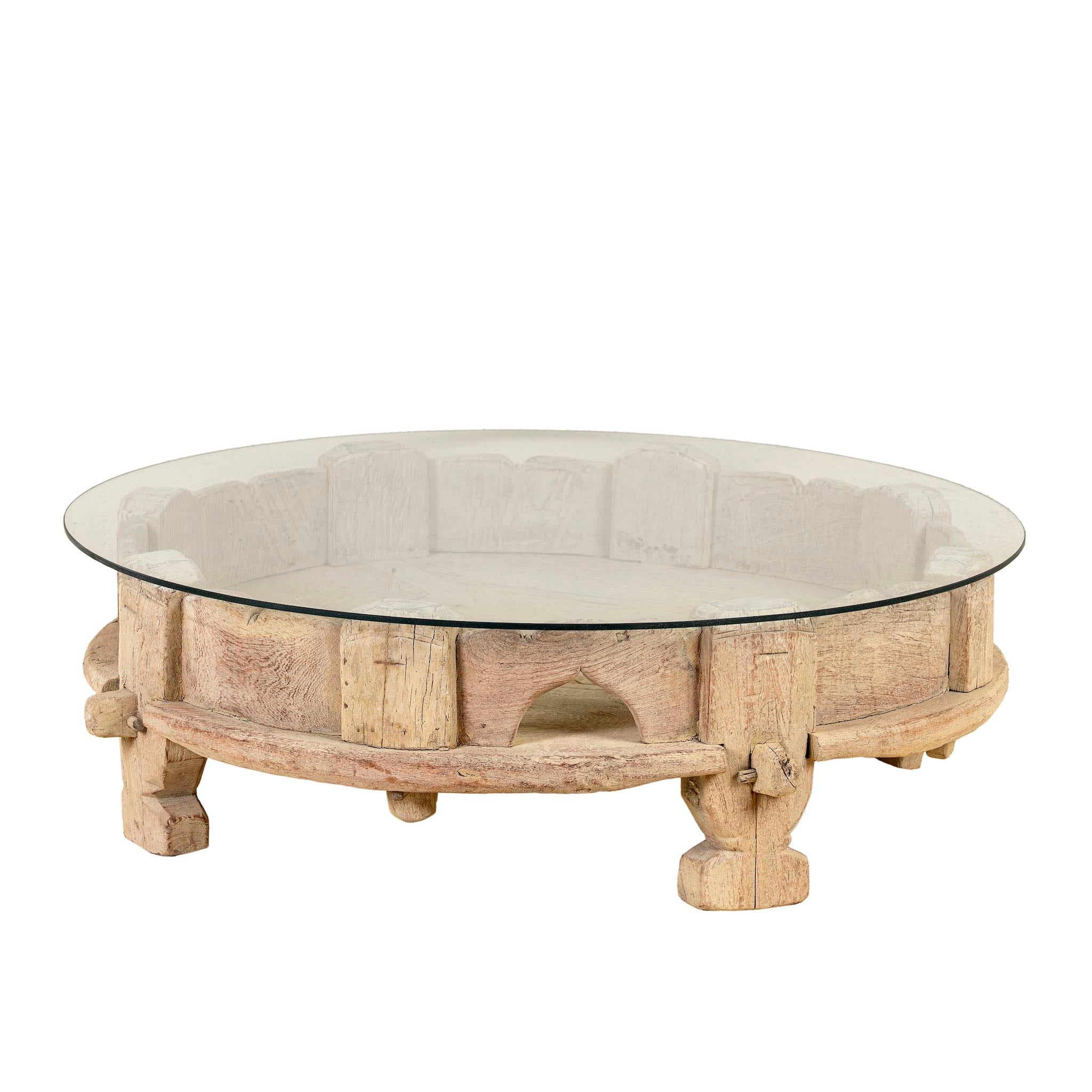 White background image of a round reclaimed teak coffee table with glass top and hand-carved base; rustic vintage design, 84 cm diameter, 28 cm height.