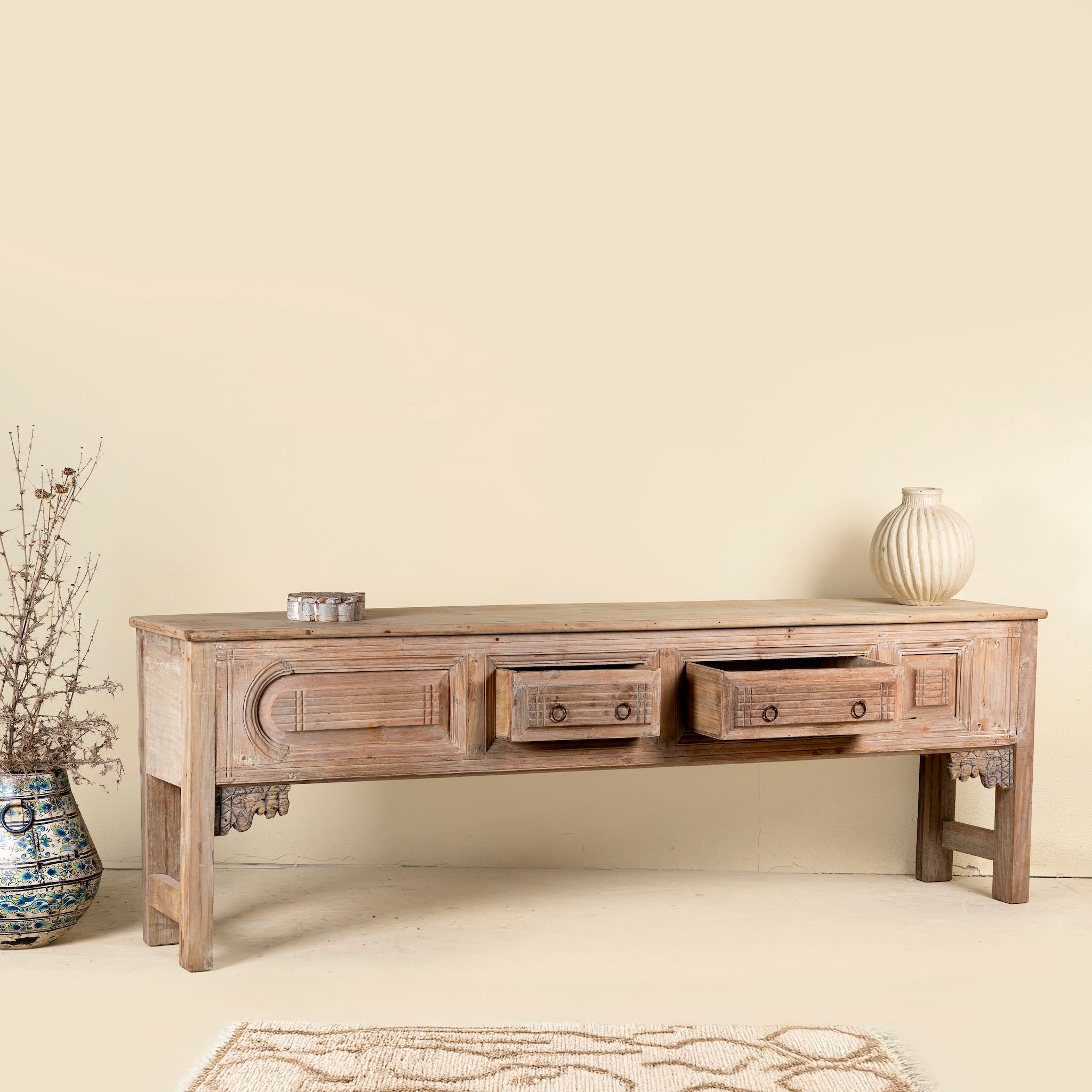 Side angle image of a carved console table made from reclaimed teak, a striking piece of unique wooden furniture.