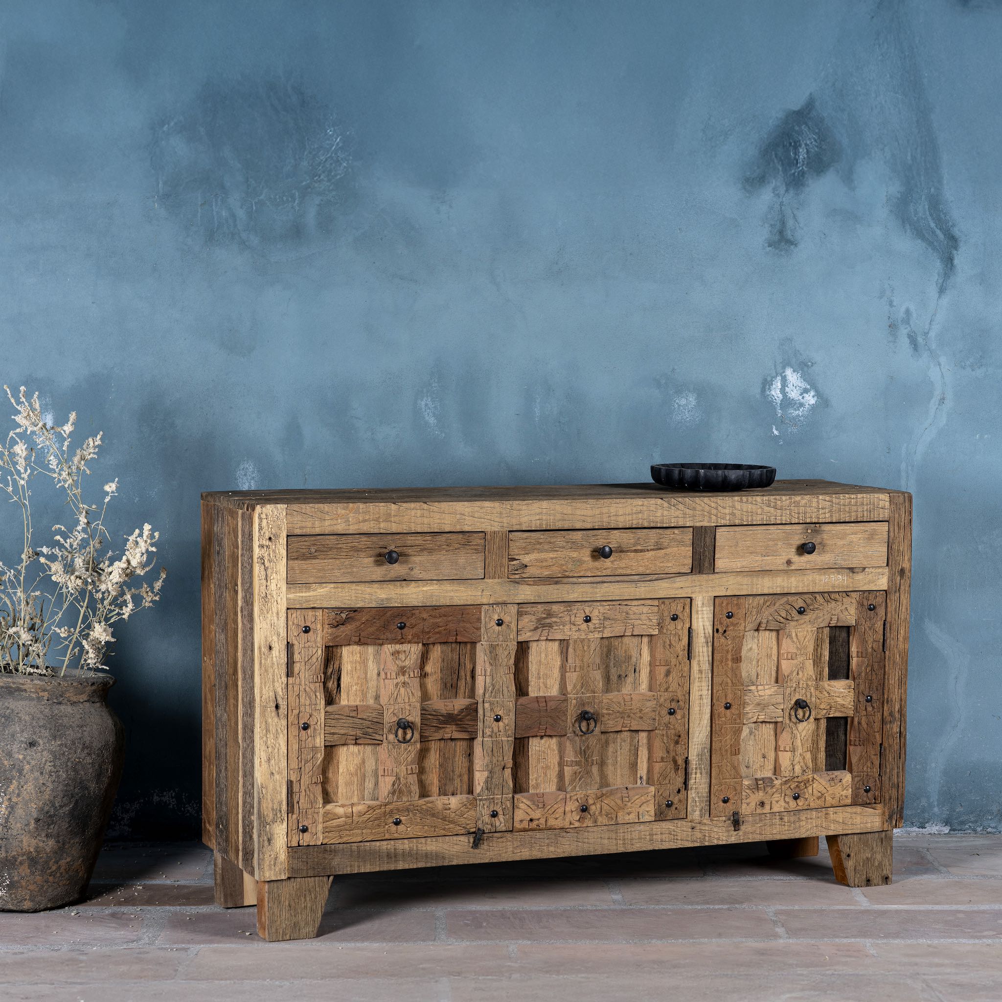 Side view image of a rustic design sideboard made from reclaimed wood with panelled doors, drawers, and iron accents; 150 × 40 × 90 cm.