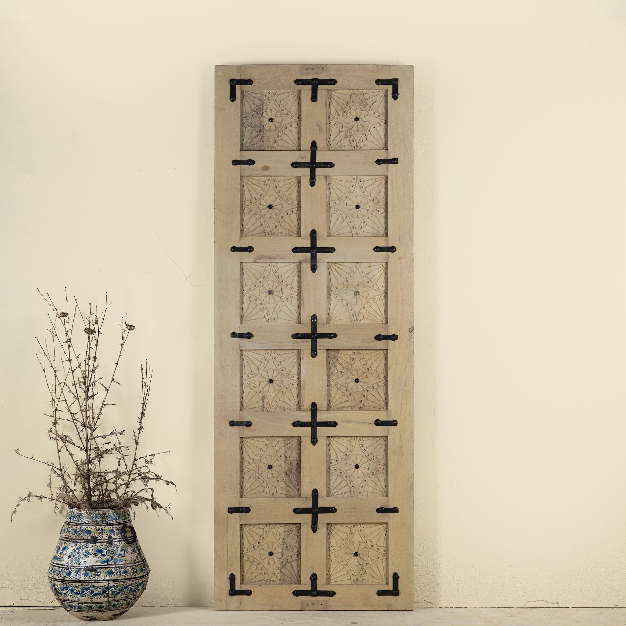 Sliding door panel made from reclaimed wood with detailed hand carvings and traditional iron fittings, combining rustic elegance with functional design.
