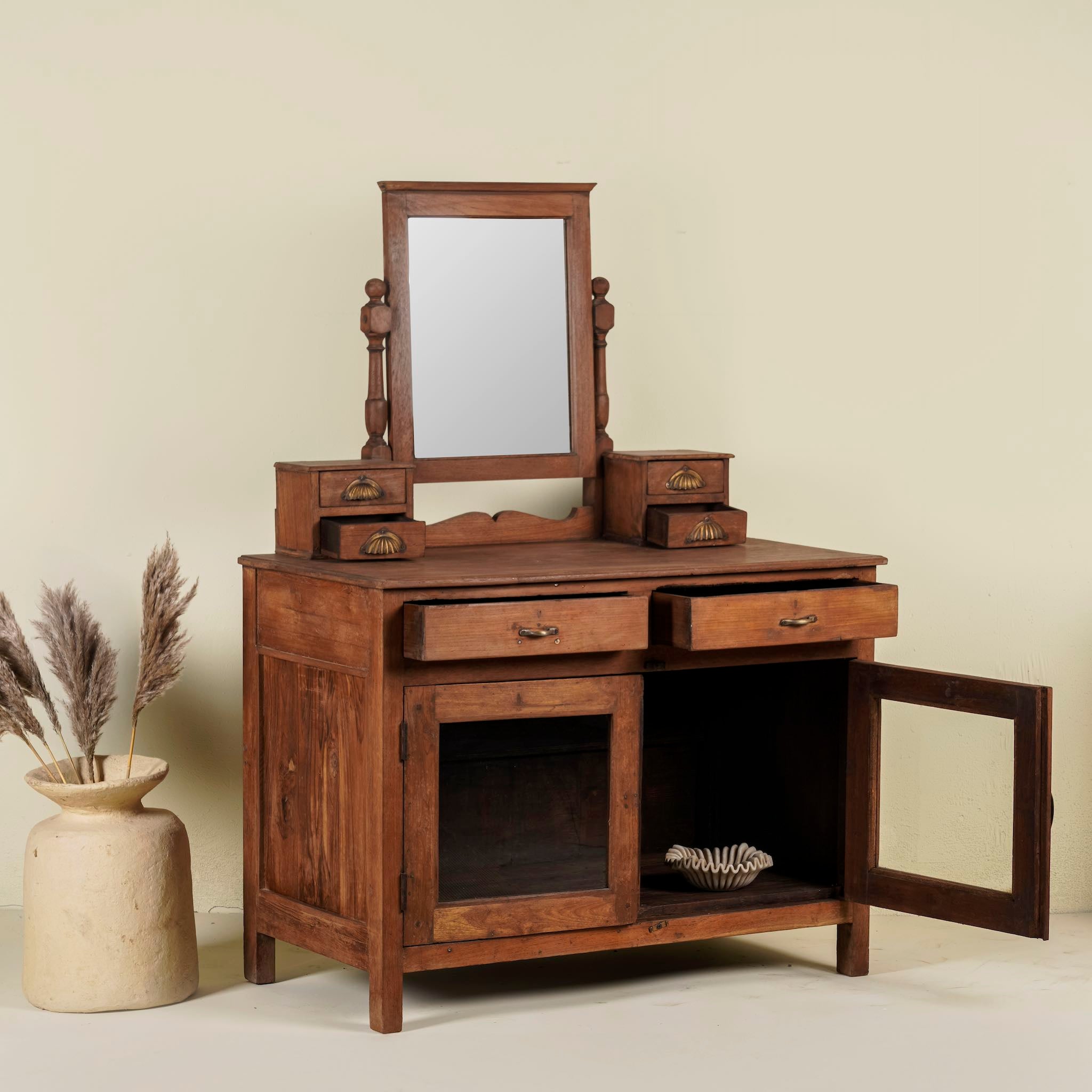 Image with open doors of a restored antique cosmetic table in teak wood with hand-carved details; teak wood furniture for bohemian interiors, 105 × 56 × 148 cm.