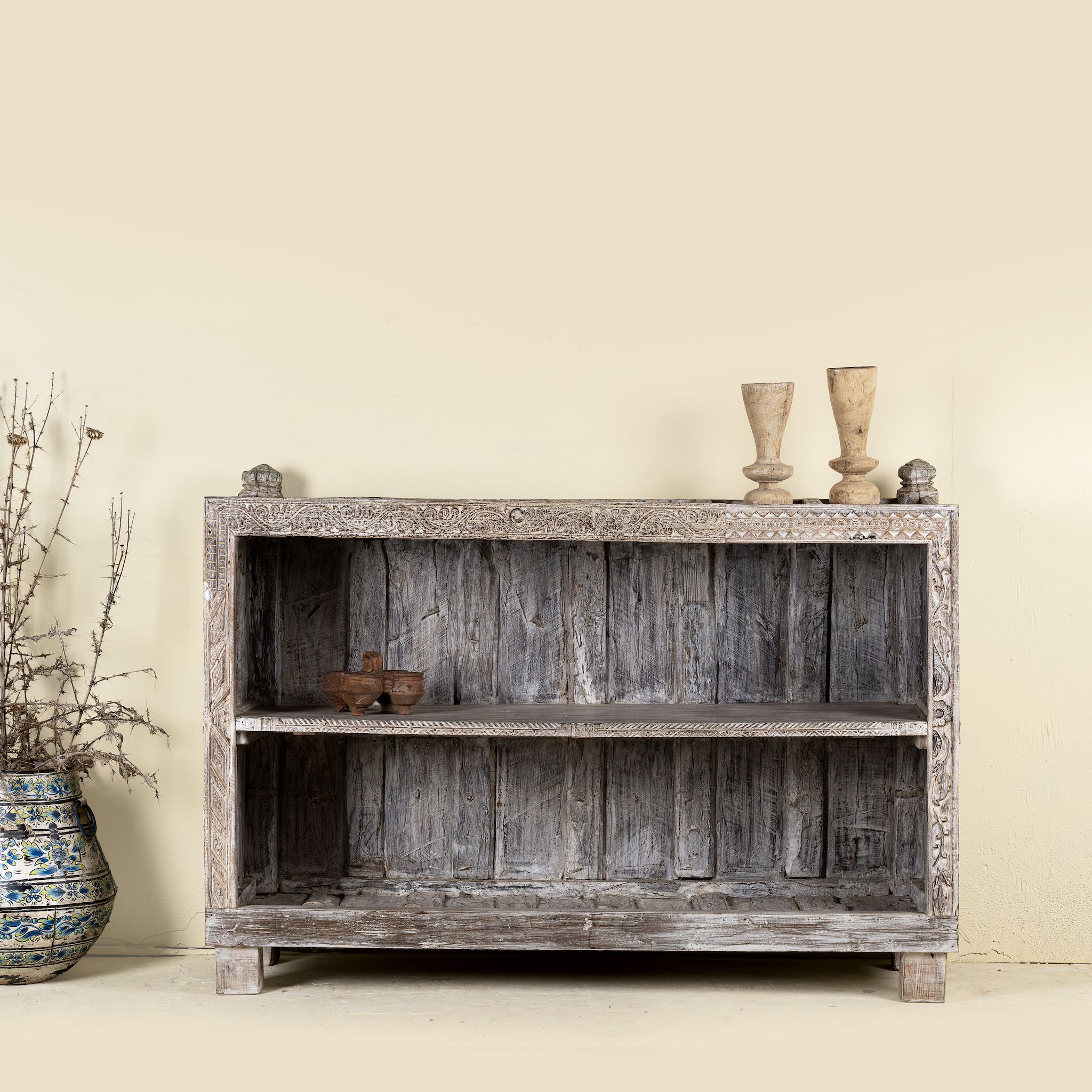 Image of the shelving space of a unique Indian furniture teak counter table with vintage shelving and aged green paint, antique console with original wood panel detailing, 152 × 64 × 102 cm.