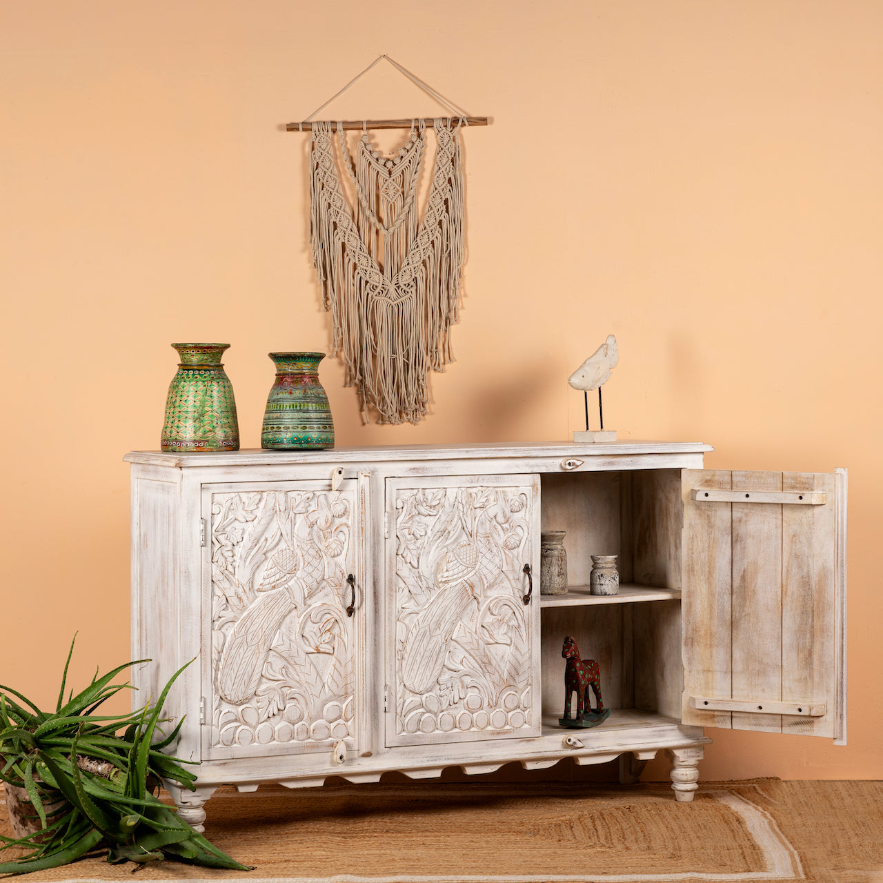 Open door image of a hand-carved mango wood sideboard with peacock and foliage motifs, whitewashed finish; perfect for Indian home decor, 150 × 95 × 40 cm.