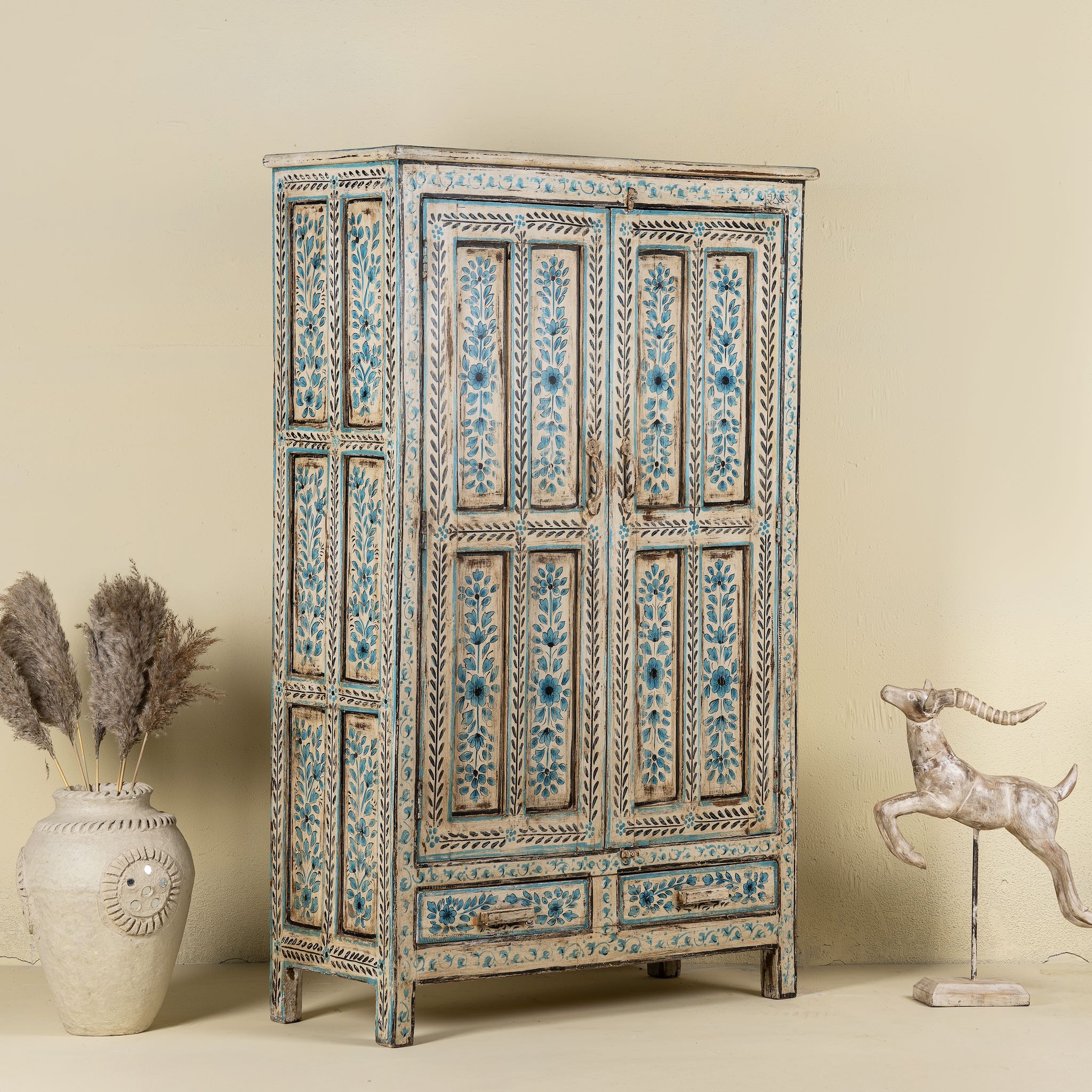 Side angle image of a hand painted wooden furniture cabinet with floral motifs, reclaimed teak artisanal furniture in Mediterranean style, 95 × 40 × 152 cm.