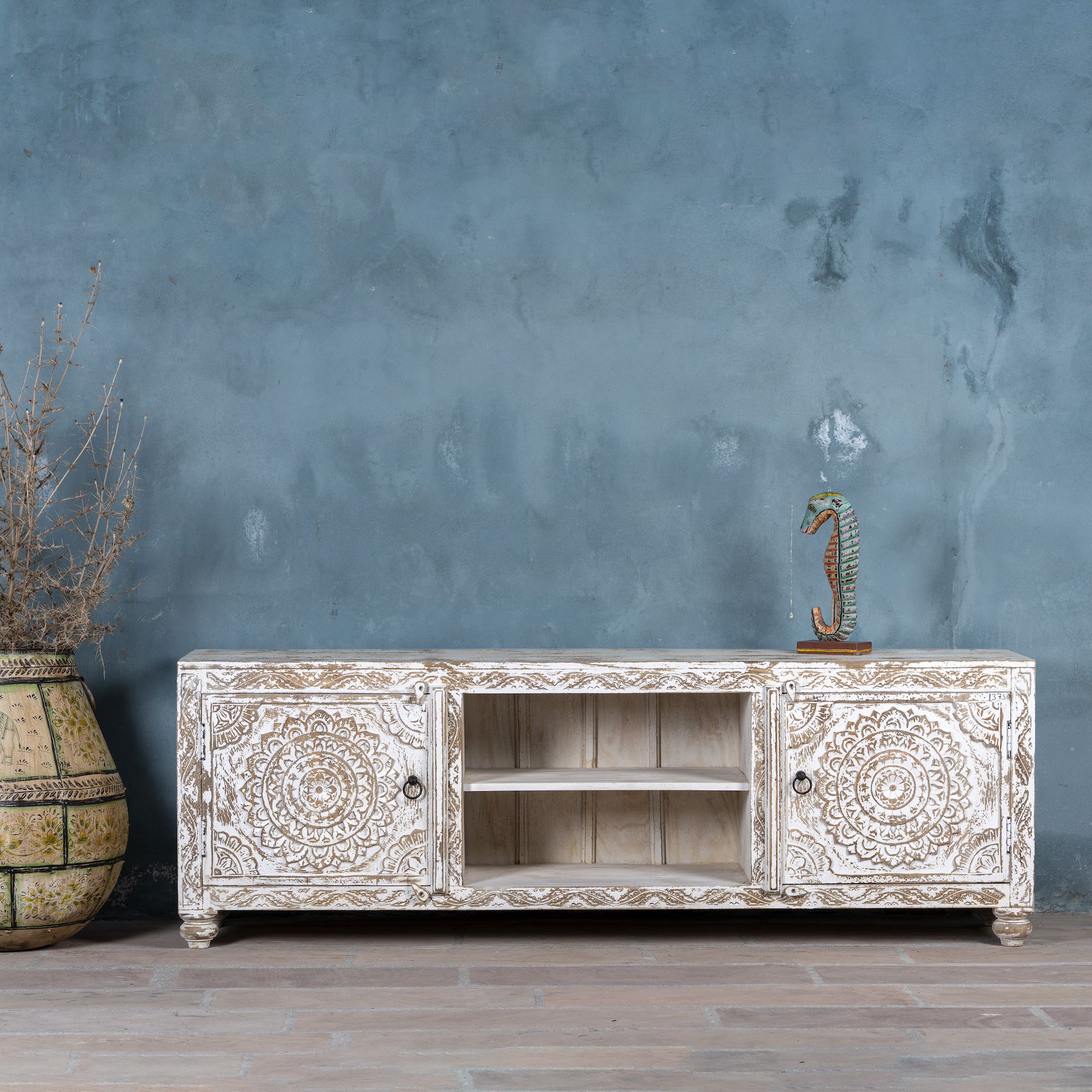 Low board made from solid mango wood, featuring intricate hand-carved mandala motifs, whitewashed finish, and practical storage with two doors and open shelving.