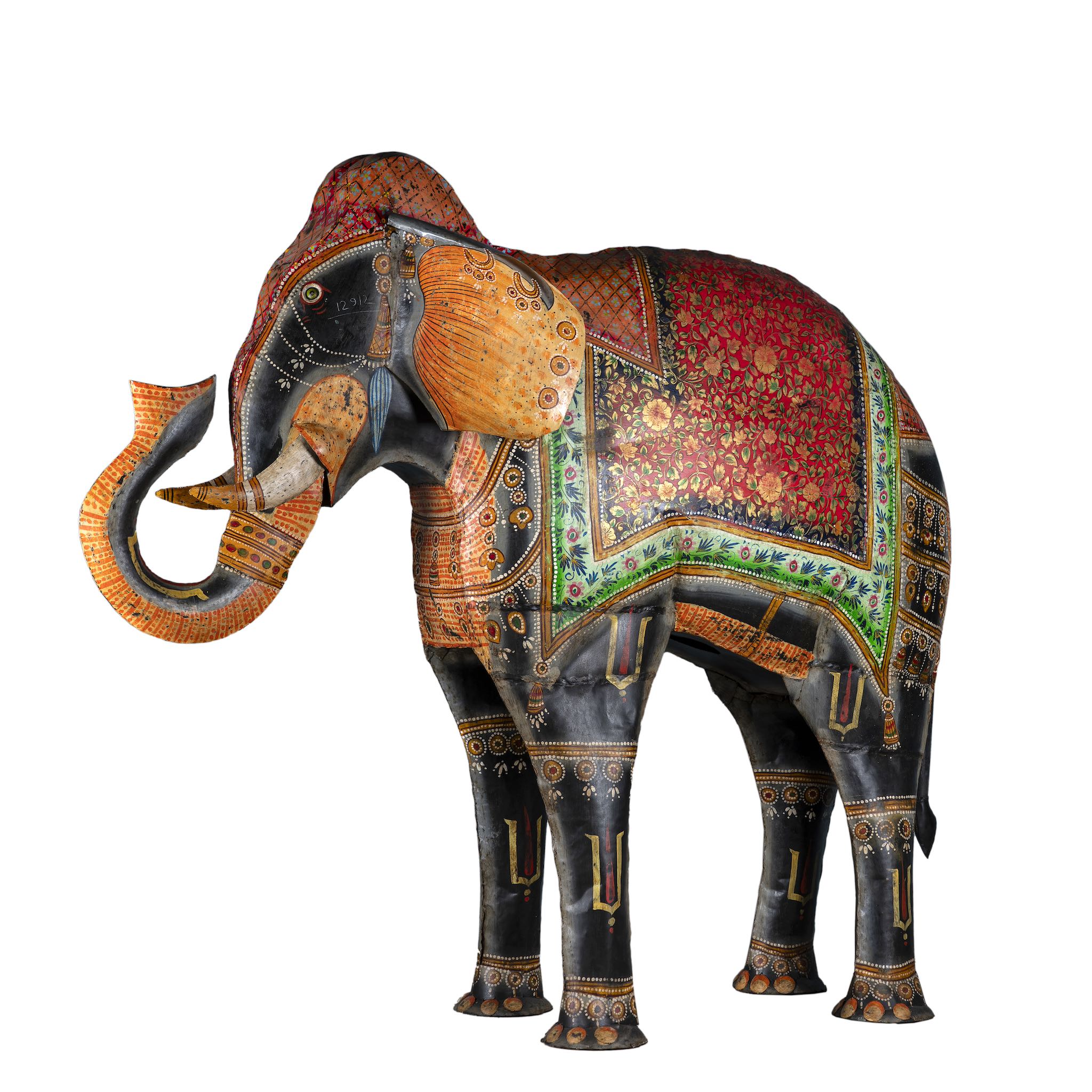 White background picture of a large hand-painted decorative elephant sculpture made of sheet metal in vibrant Rajasthani style, featuring intricate floral and geometric patterns in red, green, and gold. Ideal for enhancing entrance areas, restaurant lobbies, hotel receptions, or luxury interior spaces.