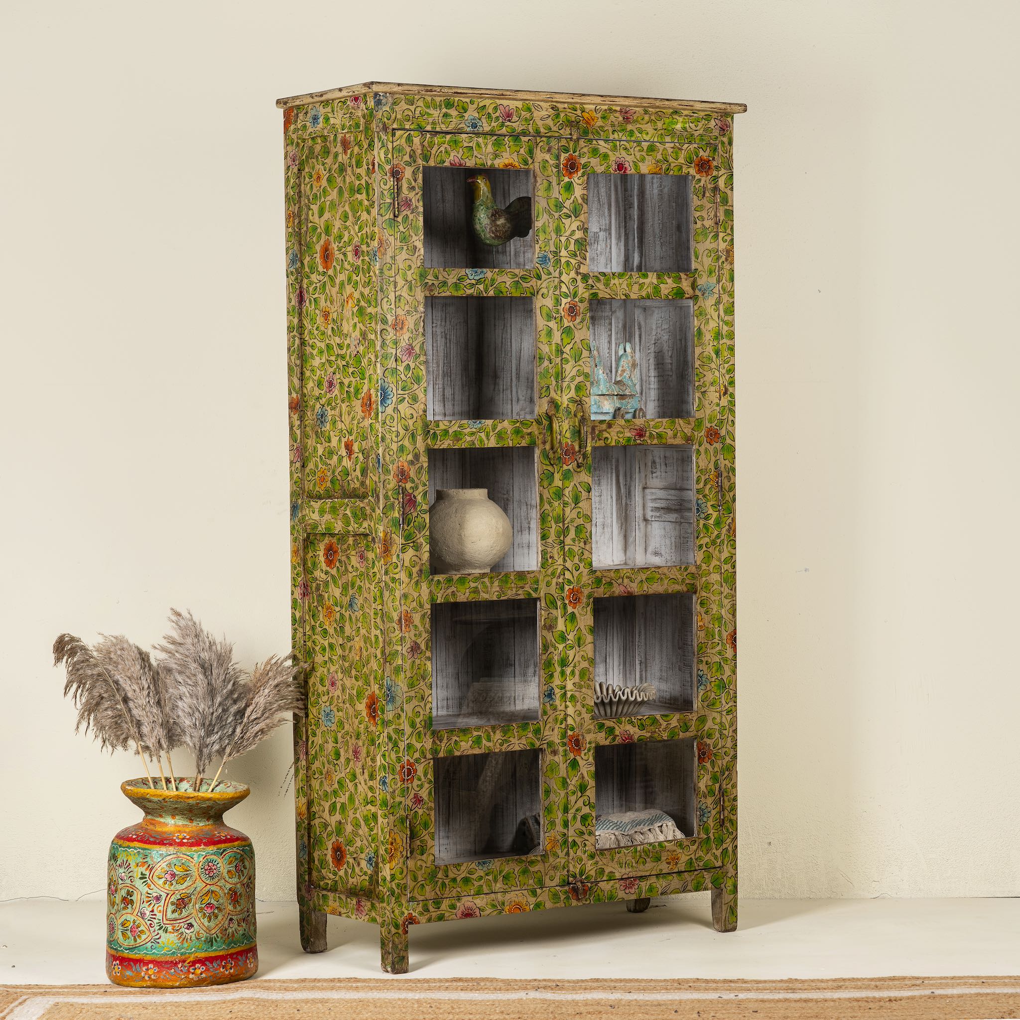 Side angle image of a hand-painted reclaimed wood showcase cabinet with floral motifs and glass doors, sustainable furniture and vintage home decor style, 96 × 40 × 182 cm.