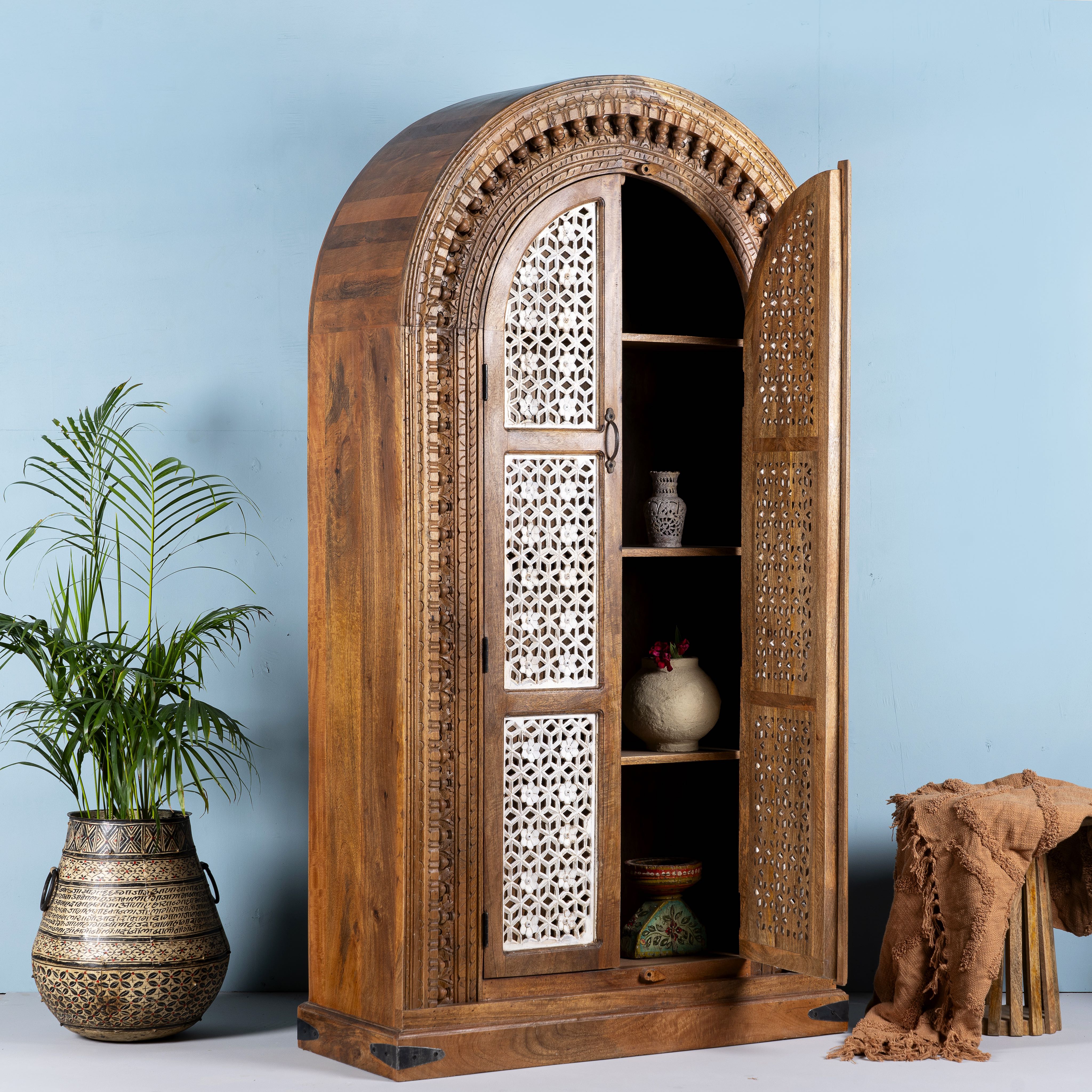 Side angle image with open doors of a handcrafted carved wooden wardrobe in half-round design with whitewashed lattice panels – bedroom furniture with Mediterranean flair and artistic detail.