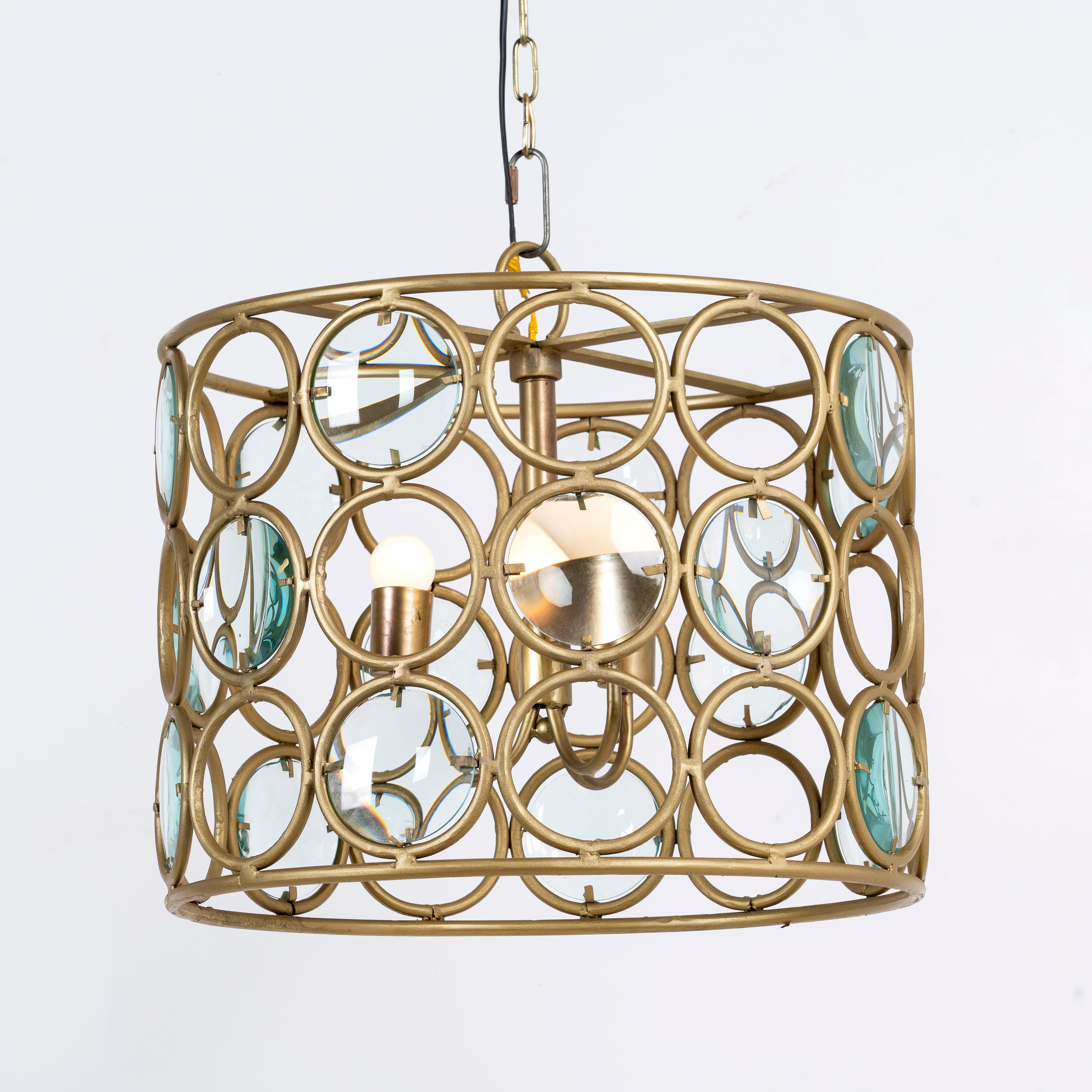 Side angle image of a round unique pendant light with shiny brass-plated iron frame and magnifying glass inserts – vintage lighting with elegant three-light design for kitchens, dining areas, or living rooms.