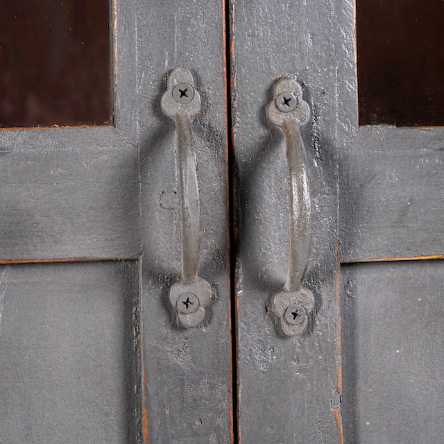 Close up image of a shabby chic teak wood cabinet with glass doors and natural reclaimed finish – sustainable furniture ideal for vintage-style dining and living spaces.