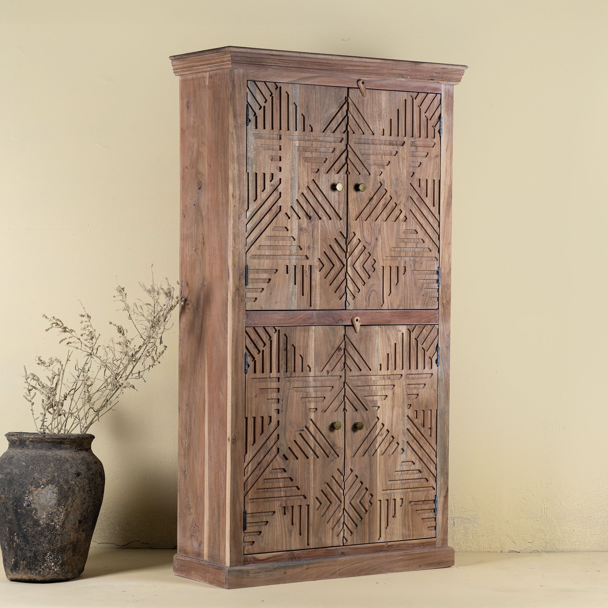 Side view of a hand crafted acacia wood cabinet with 4 doors, brass fitted door knobs and geometrical carvings.
