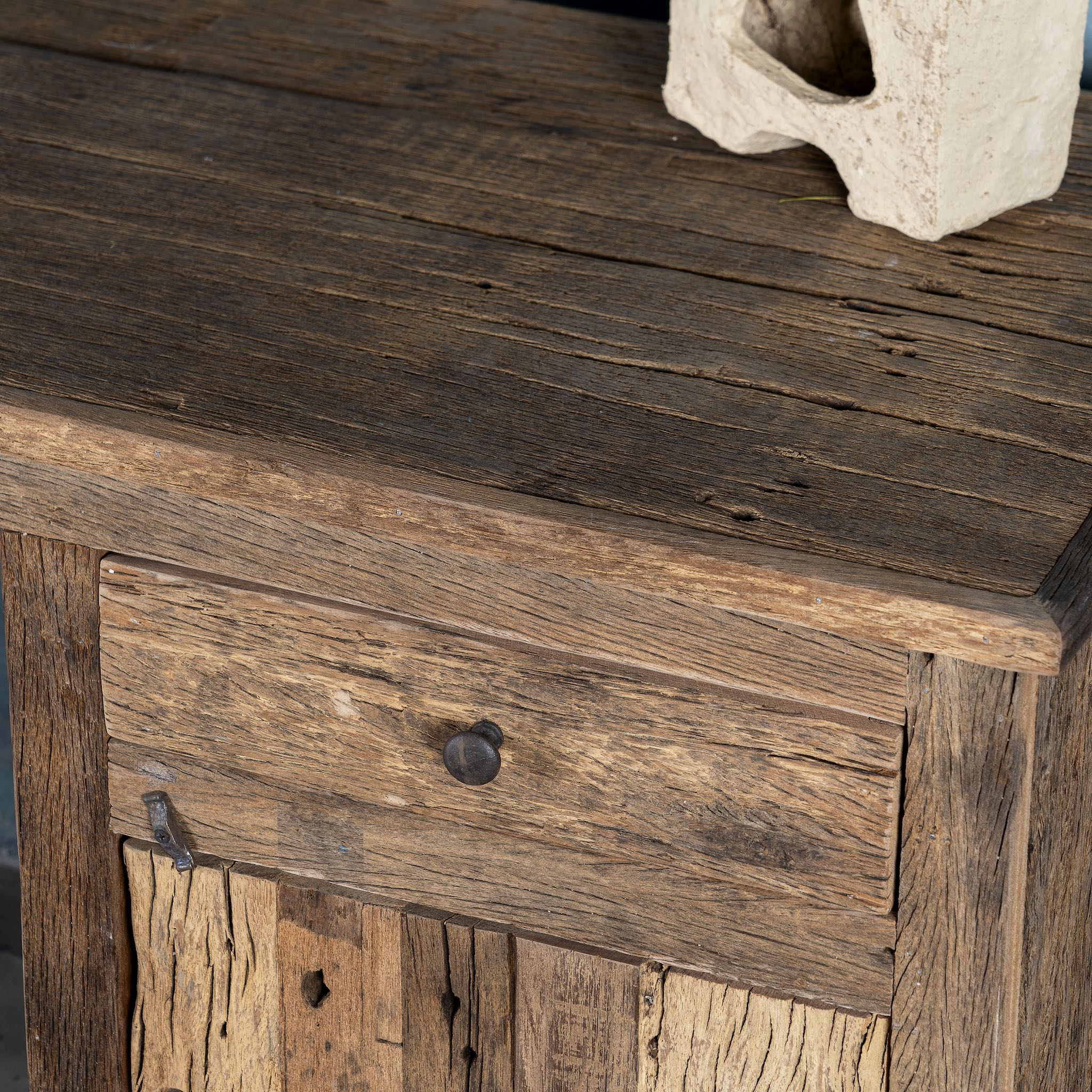 Close up image of a rustic minimalist wooden desk made from reclaimed old wood with drawer and cabinet, 130 × 60 × 75 cm.