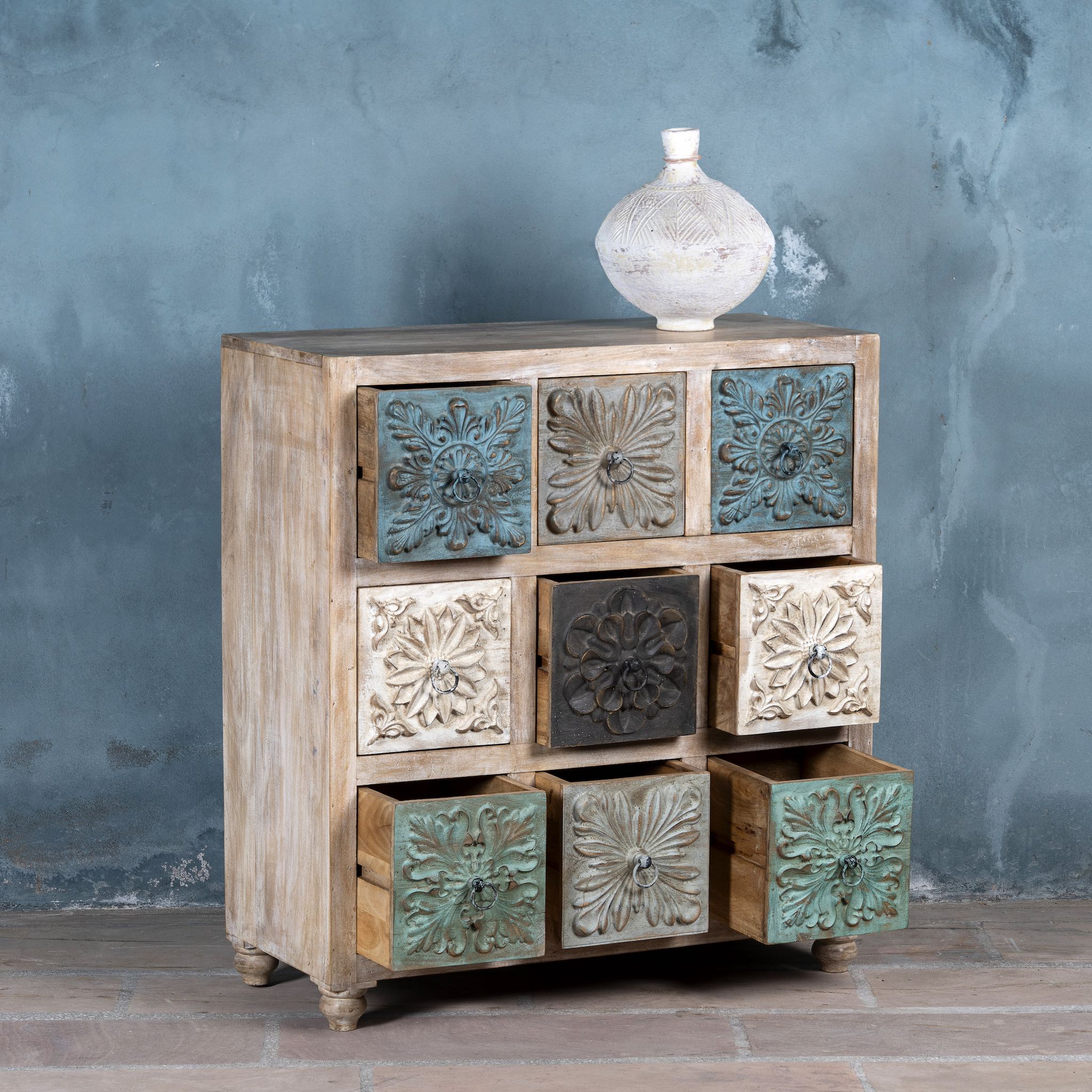 Wooden cabinet with decorative embossed panels against a textured gray wall.