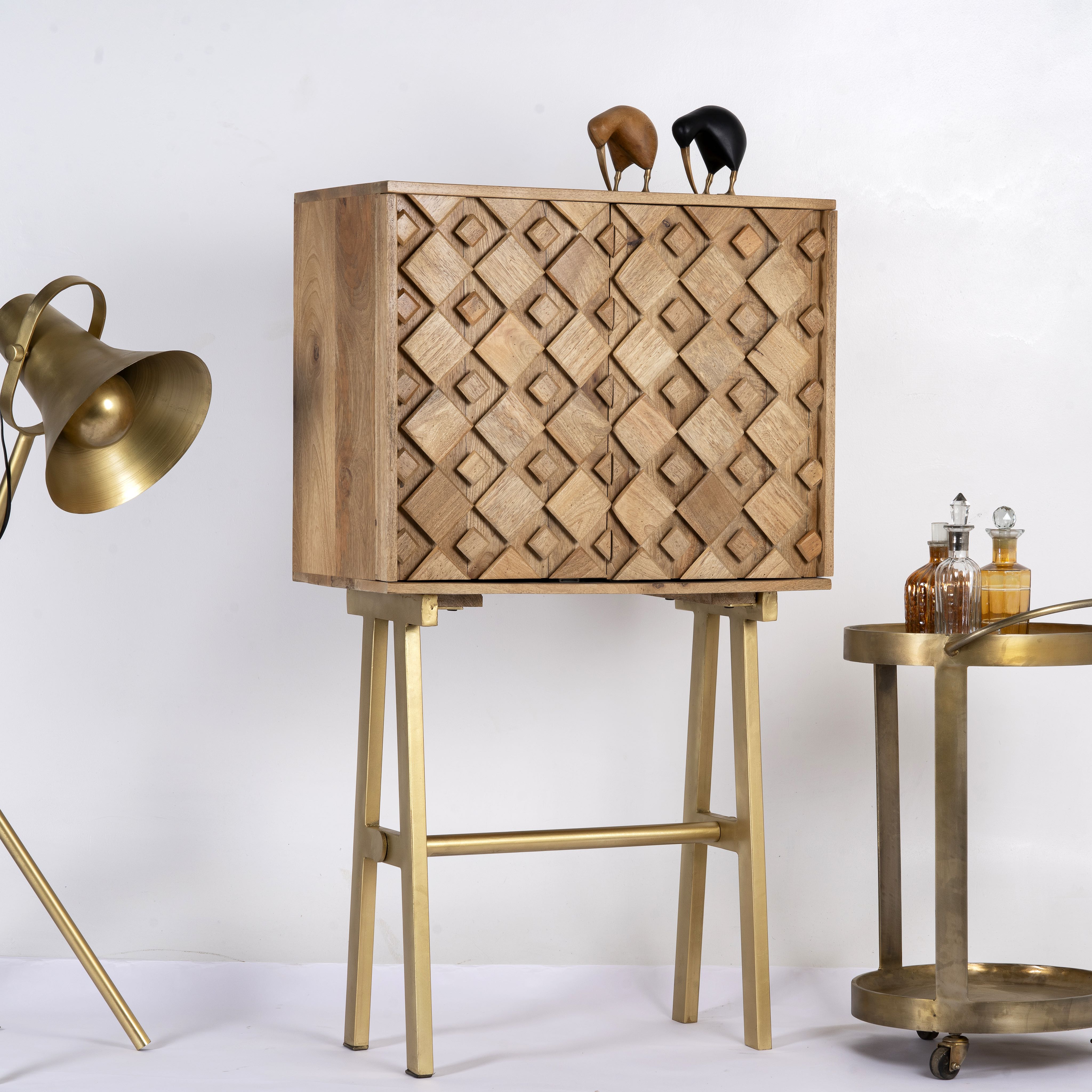 Side angle image of a tall mango wood cabinet in grey sandblasted finish with geometric sunburst design and brass handles, 76 × 38 × 135 cm.