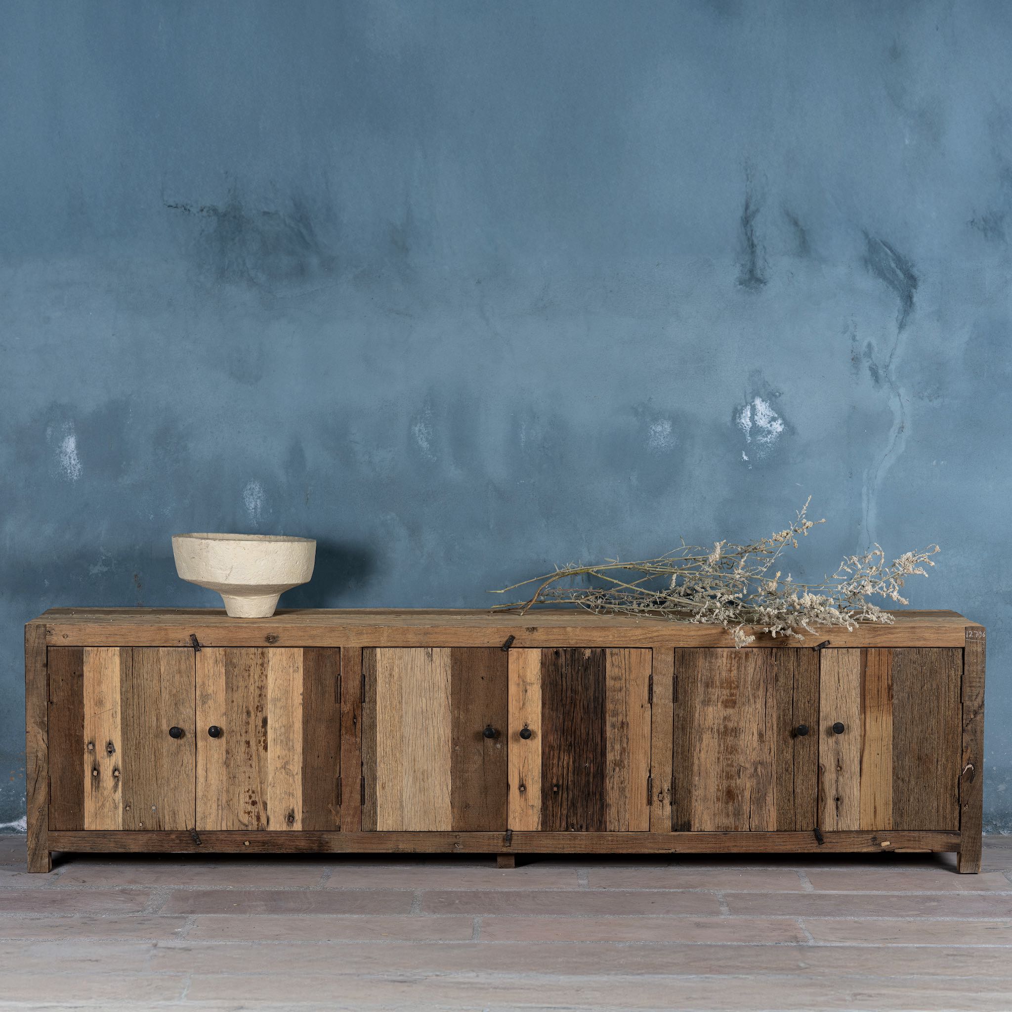 Lifestyle image of a sustainable driftwood furniture lowboard made from reclaimed wood with four cabinets and rustic finish; 230 × 45 × 60 cm.