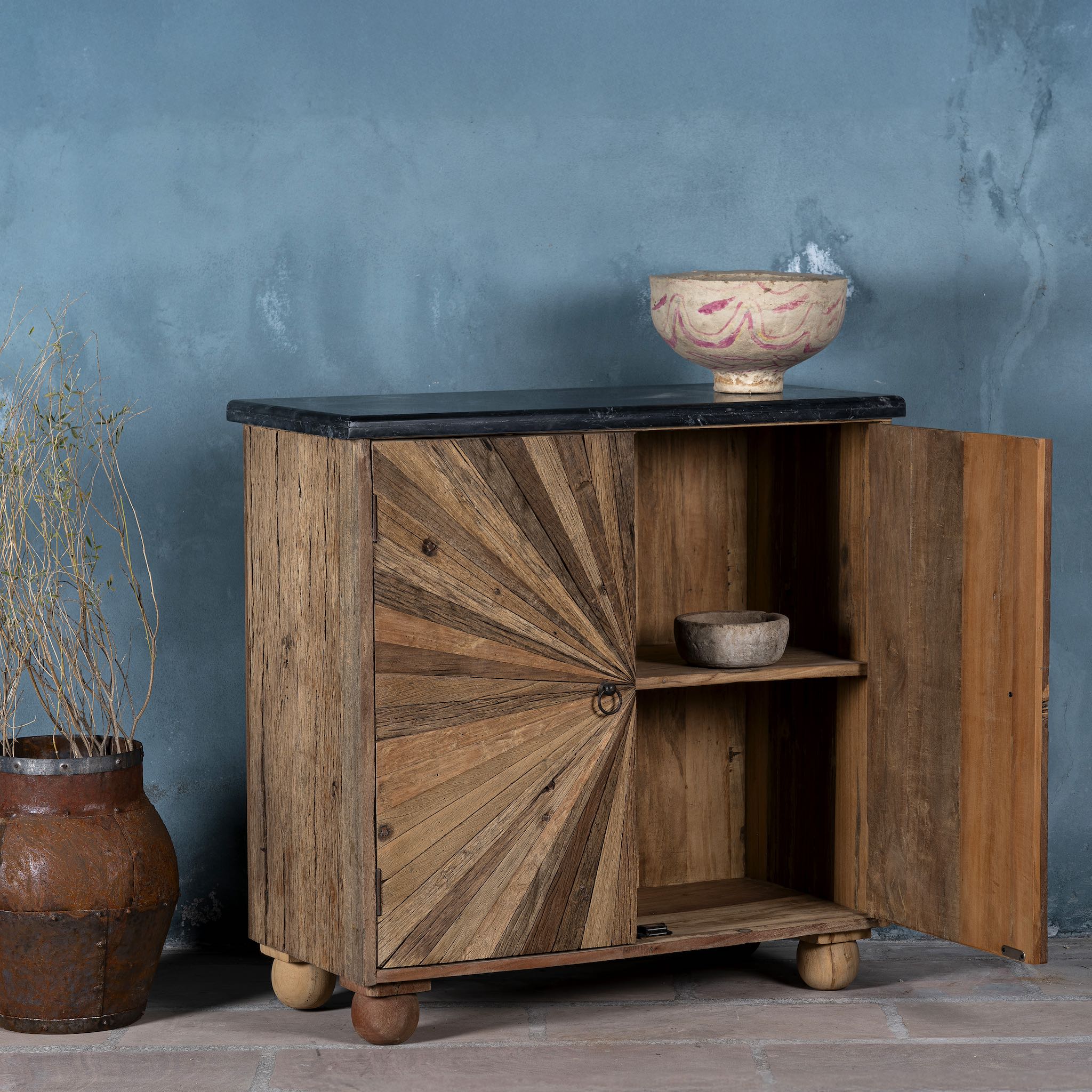 Open door image of a reclaimed wood sideboard with sunburst carved doors, sliding black marble top, and rustic finish, ideal for rustic interior design.