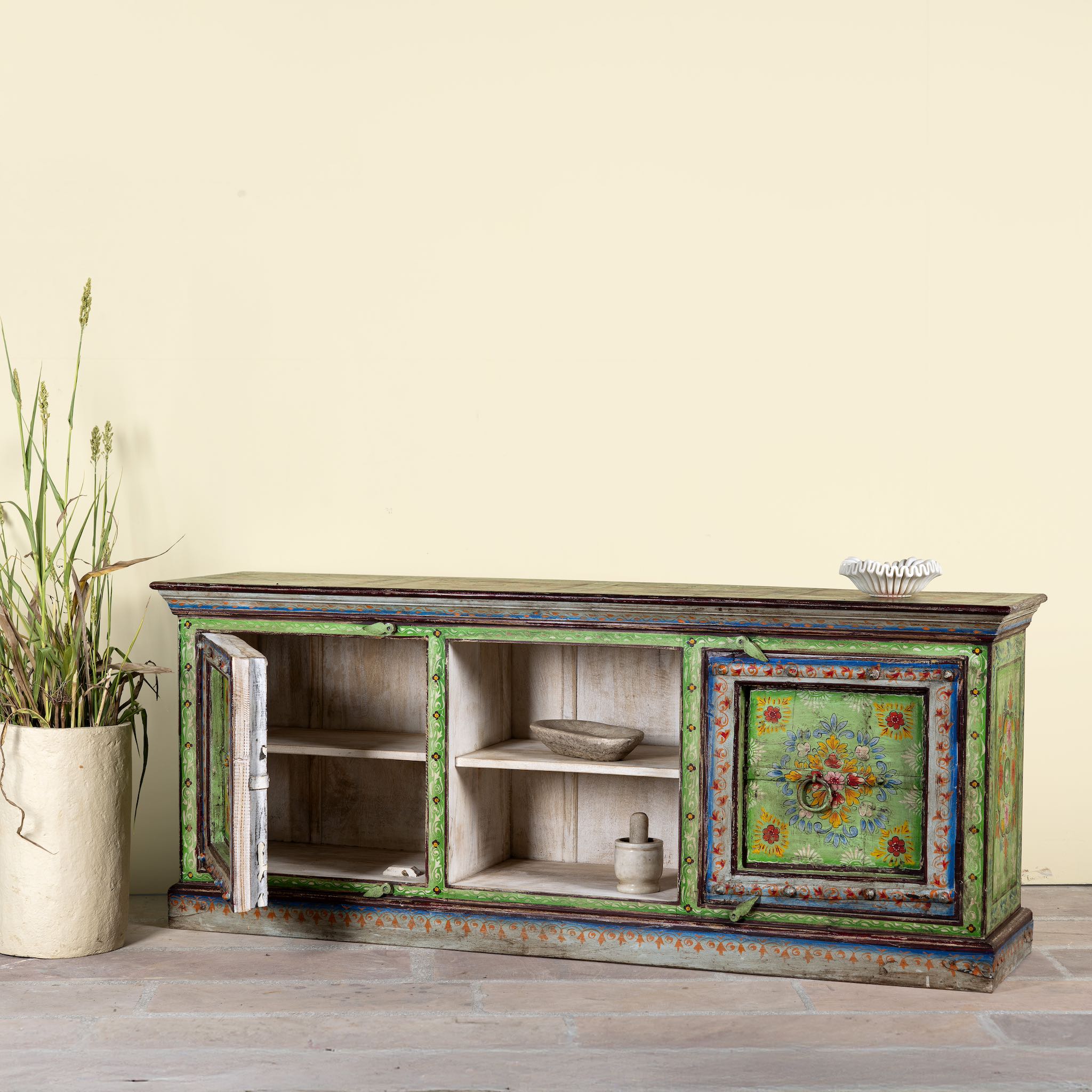 Side angle image showing open doors of a hand-painted reclaimed wood vintage lowboard with floral motifs – a colourful piece of sustainable furniture for artistic and rustic interiors.