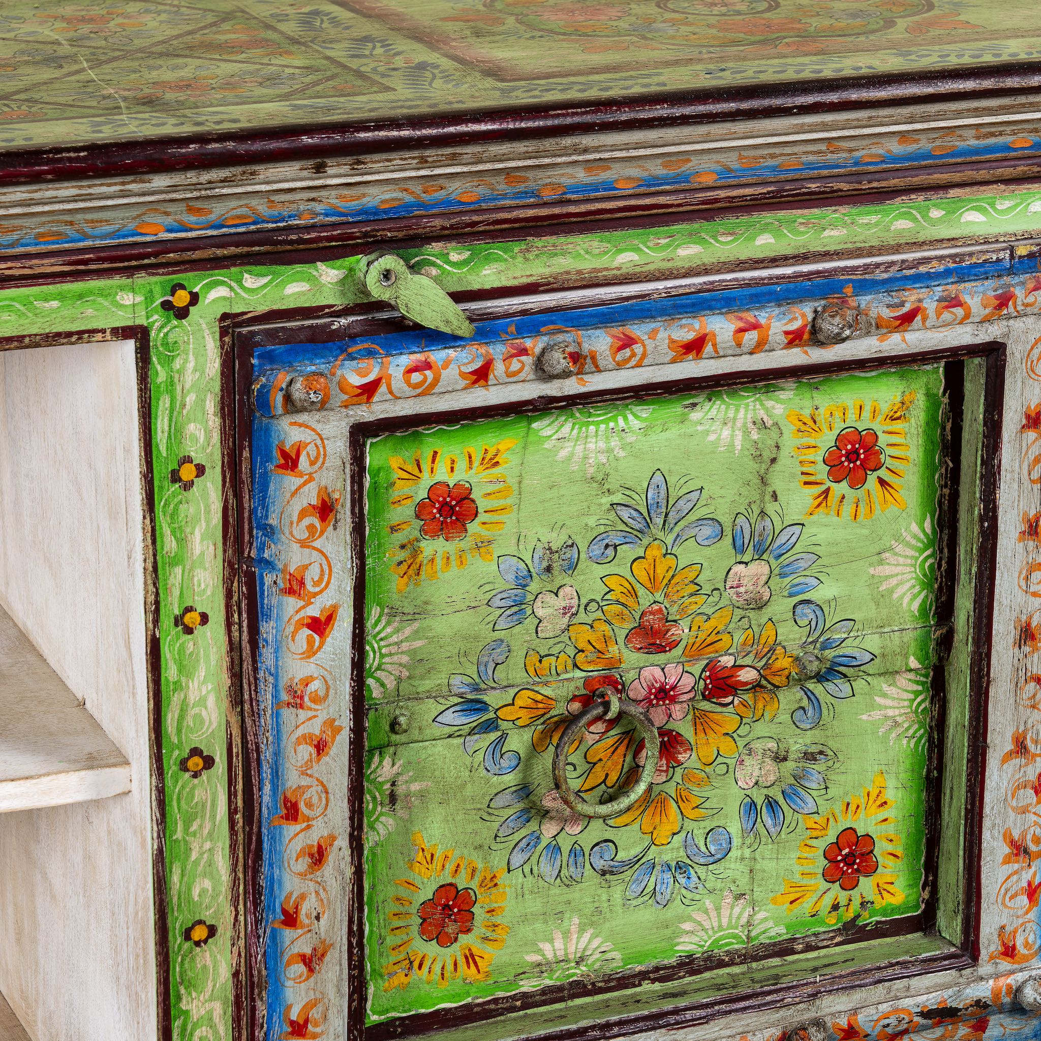 Close up image of a hand-painted reclaimed wood vintage lowboard with floral motifs – a colourful piece of sustainable furniture for artistic and rustic interiors.