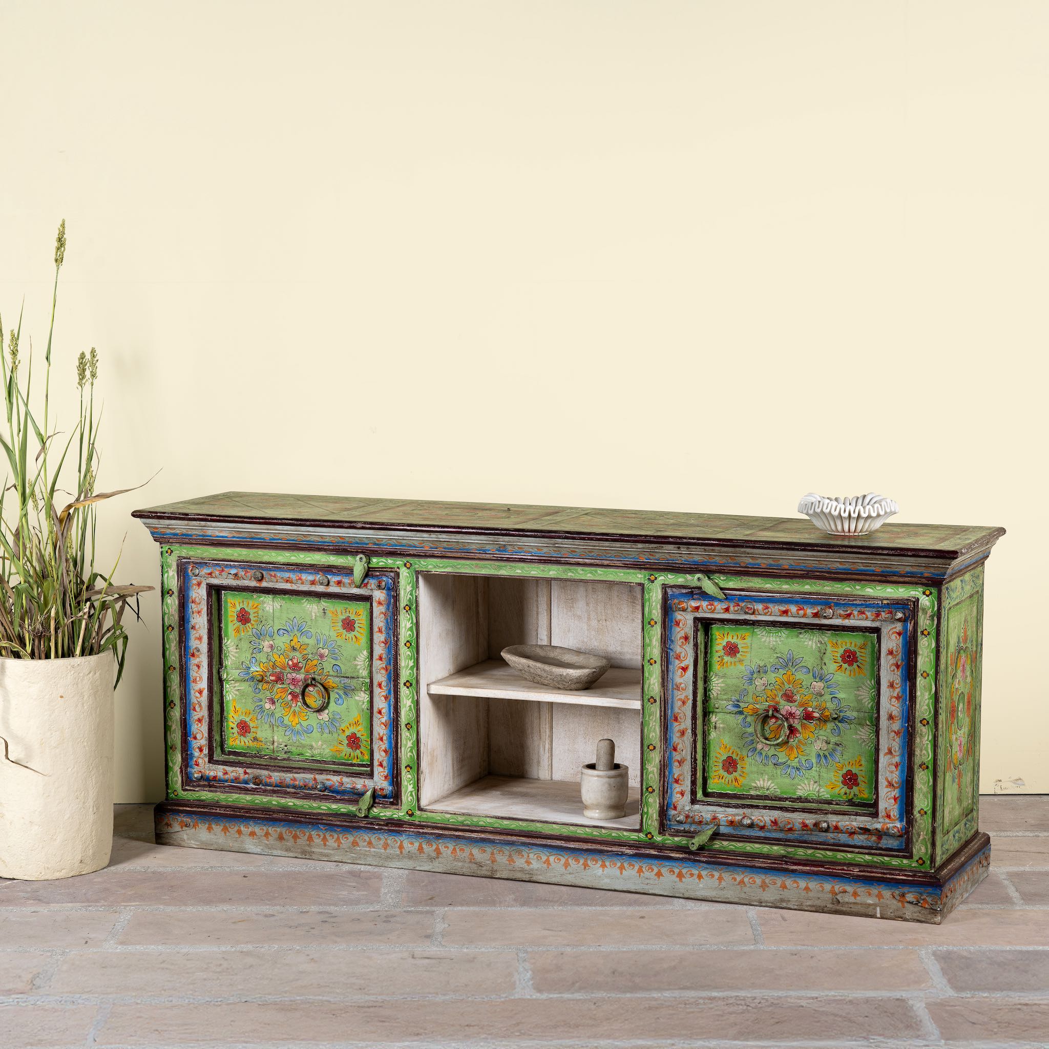 Side angle image of a hand-painted reclaimed wood vintage lowboard with floral motifs – a colourful piece of sustainable furniture for artistic and rustic interiors.