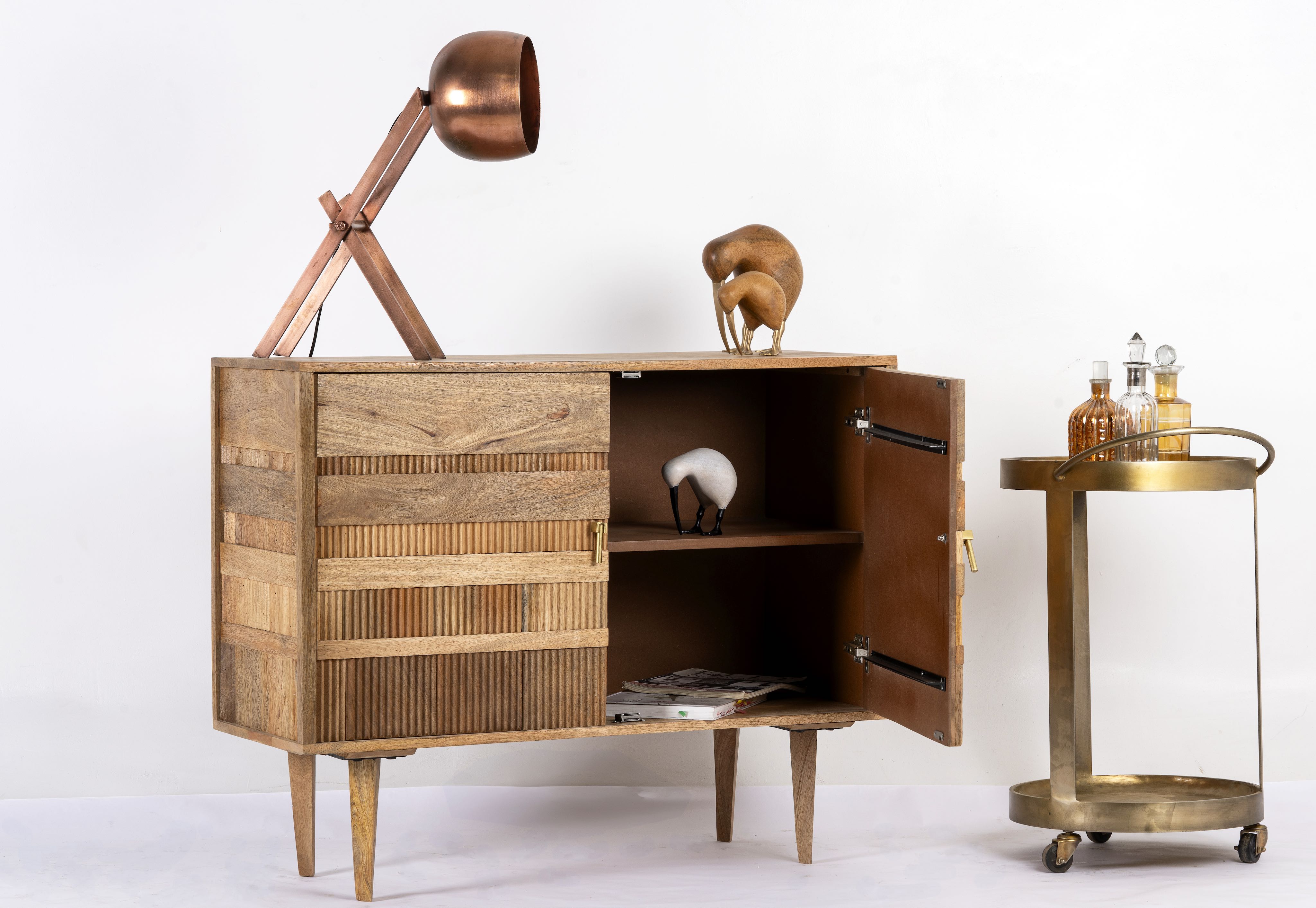 Side angle image with open door of a hand-carved mango wood cabinet with 3D line-striped design and natural finish—vintage furniture blending artisanal detail and timeless style.