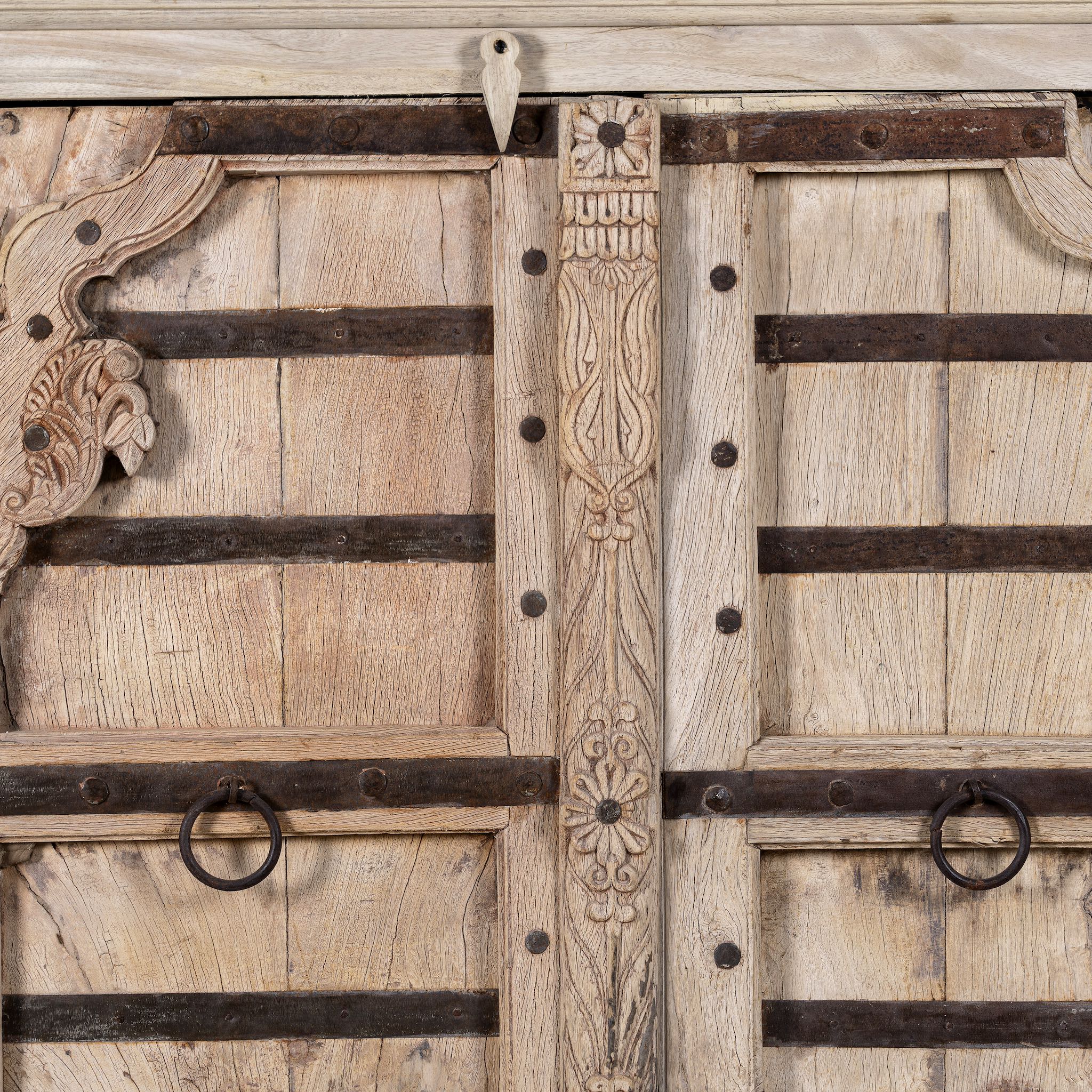 Close up image of a reclaimed teak furniture sideboard with antique Indian doors, old door cabinet with hand-carved details and iron accents, 220 × 45 × 110 cm.