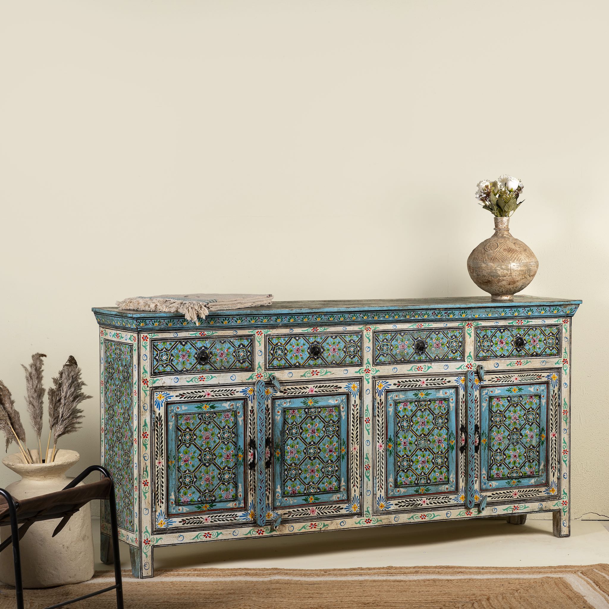 Side angle image of a hand painted furniture sideboard made from reclaimed teak wood with floral motifs, artisanal furniture in bohemian Mediterranean style, 180 × 40 × 90 cm.