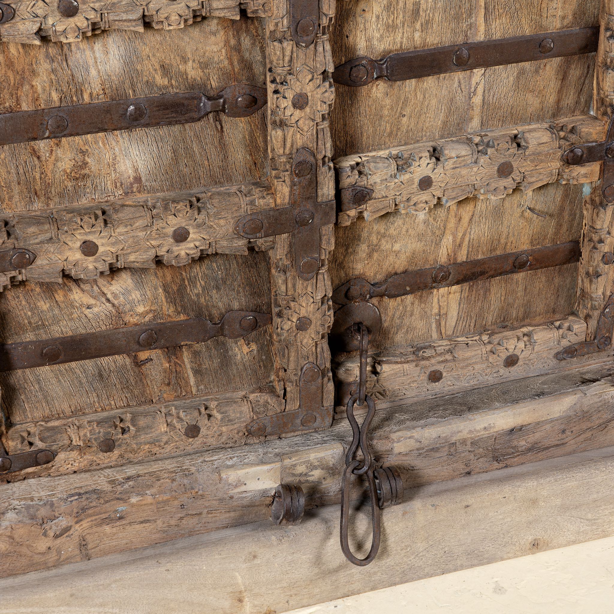 Close-up of an old wooden door with metal hinges and locks on a cabinet with antique carved teak door, part of our teak wood furniture collection, perfect for a bohemian interior.
