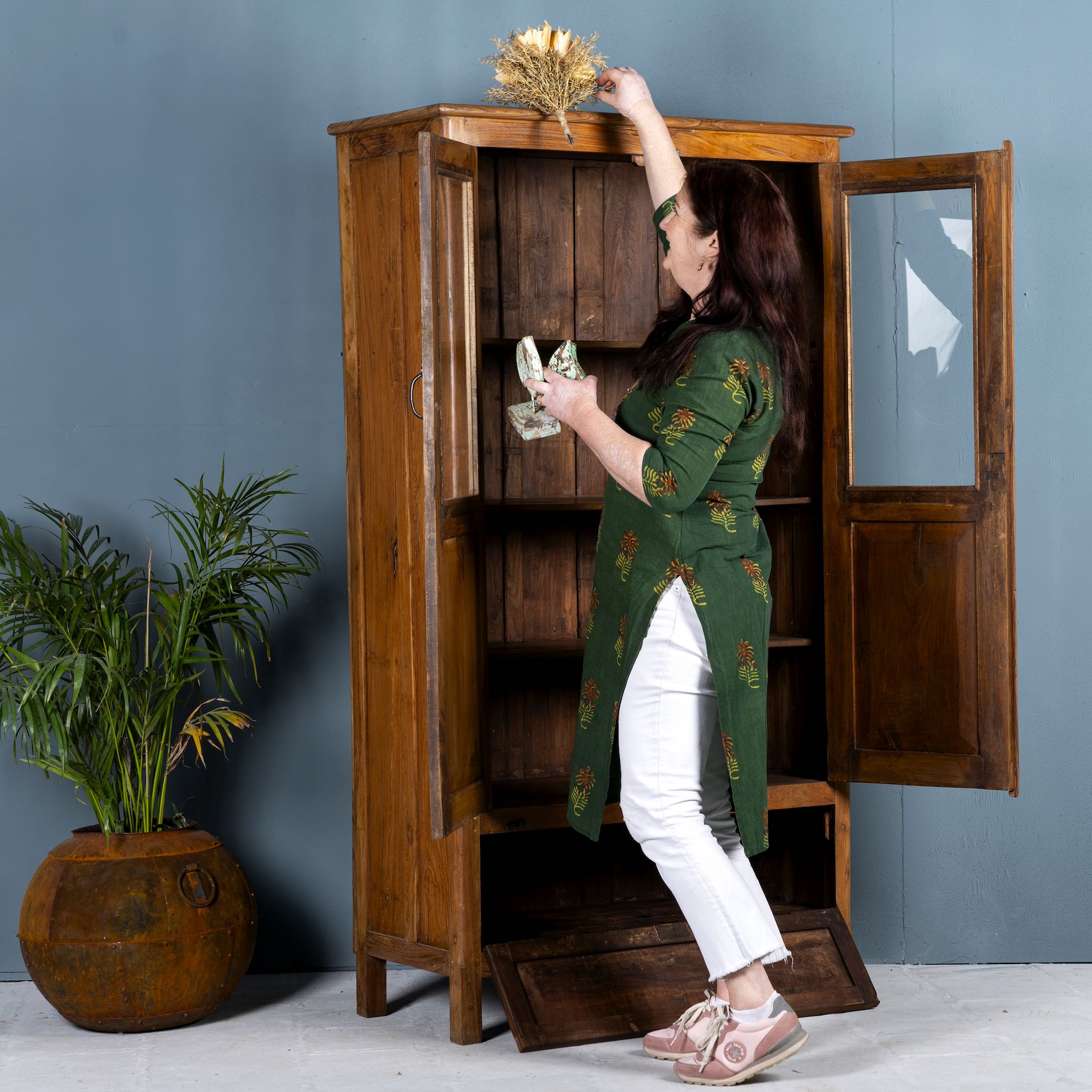 Tall reclaimed teak wood display cabinet with two glass doors and a bottom drawer – wooden display cabinet crafted as sustainable furniture with natural elegance.