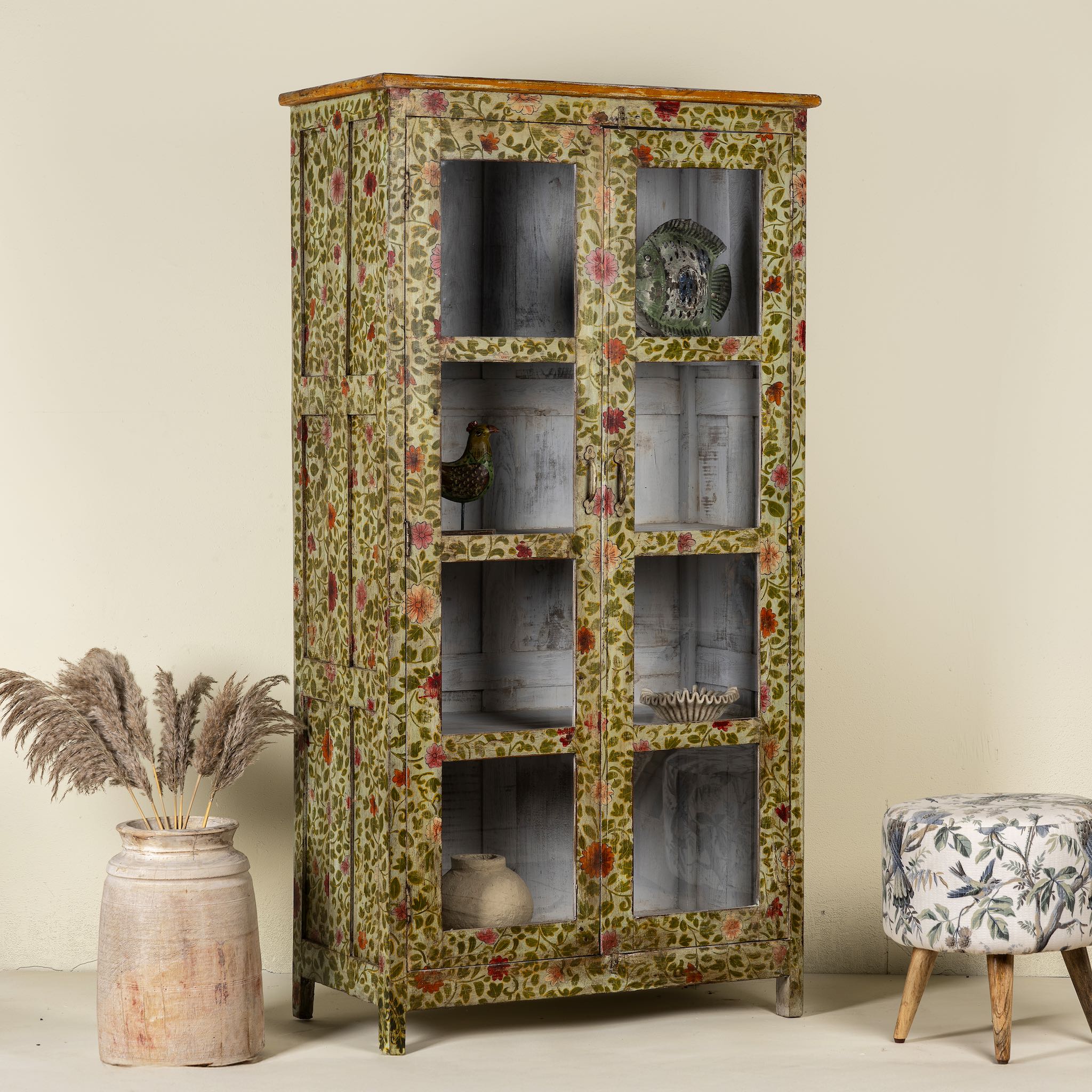 Side angle image of a hand-painted reclaimed wood showcase cabinet with floral motifs and glass doors, sustainable furniture and vintage home decor style, 95 × 48 × 183 cm.