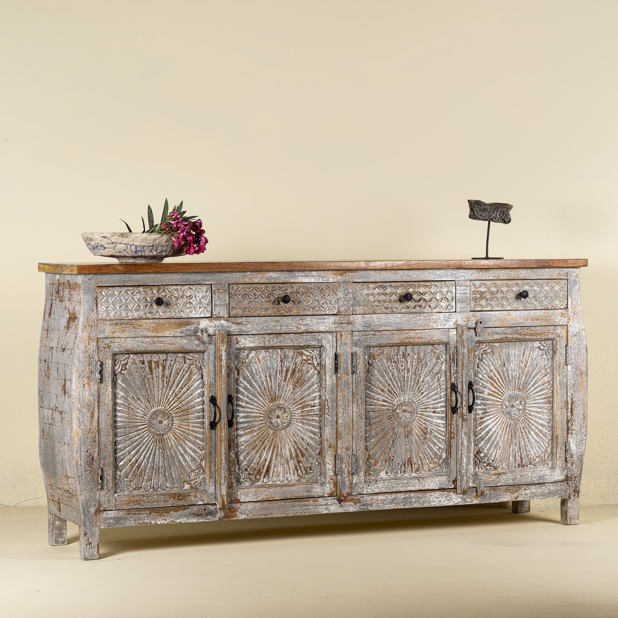 Side angle image of a living room furniture sideboard made from hand-carved mango wood, vintage style furniture with sunburst patterns and distressed finish, 180 × 40 × 90 cm.