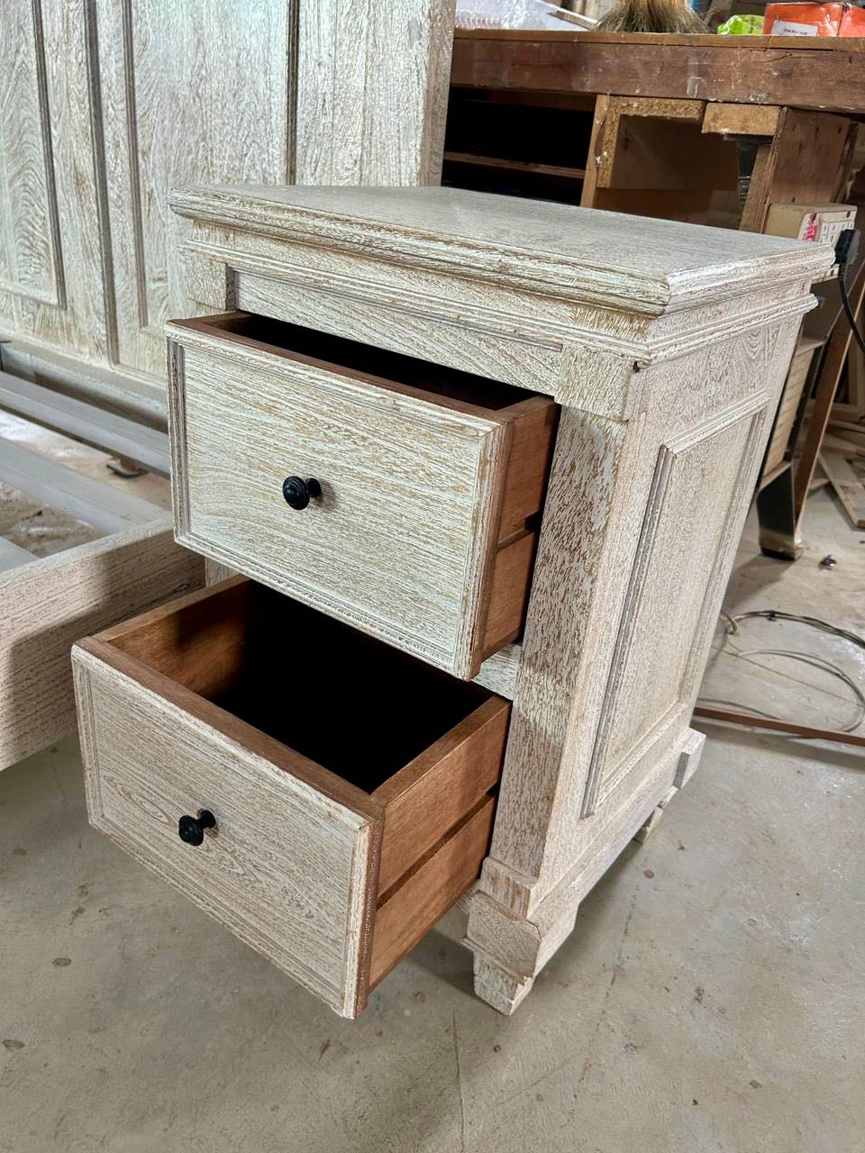 Close up of the fitting nightstand of a whitewashed mango wood bed frame with carved panel design and two matching nightstands; rustic bedroom furniture set, bed size 180×200×140 cm, nightstands 50×40×65 cm.