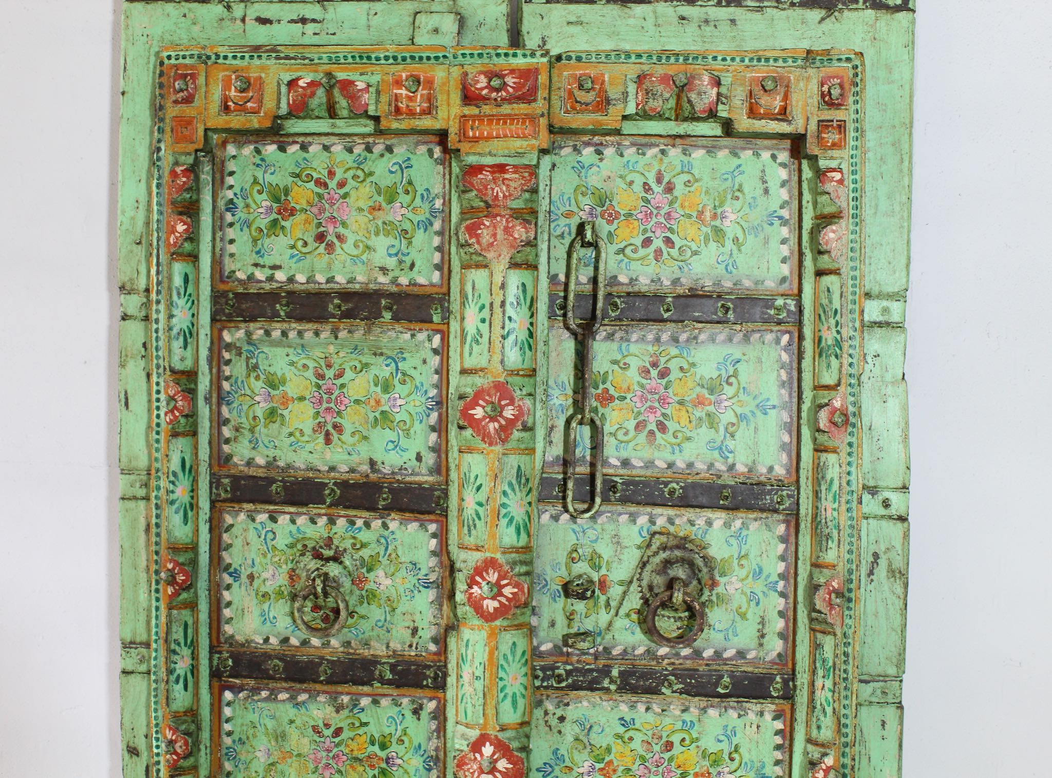 Close up image of a hand-painted old Indian teak door with floral motifs in vintage style.