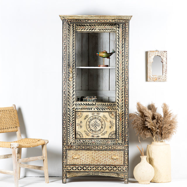 A vintage-style Pattanur showcase cabinet with hand-painted floral and geometric patterns, featuring a bird perched on a shelf with decorative items.
