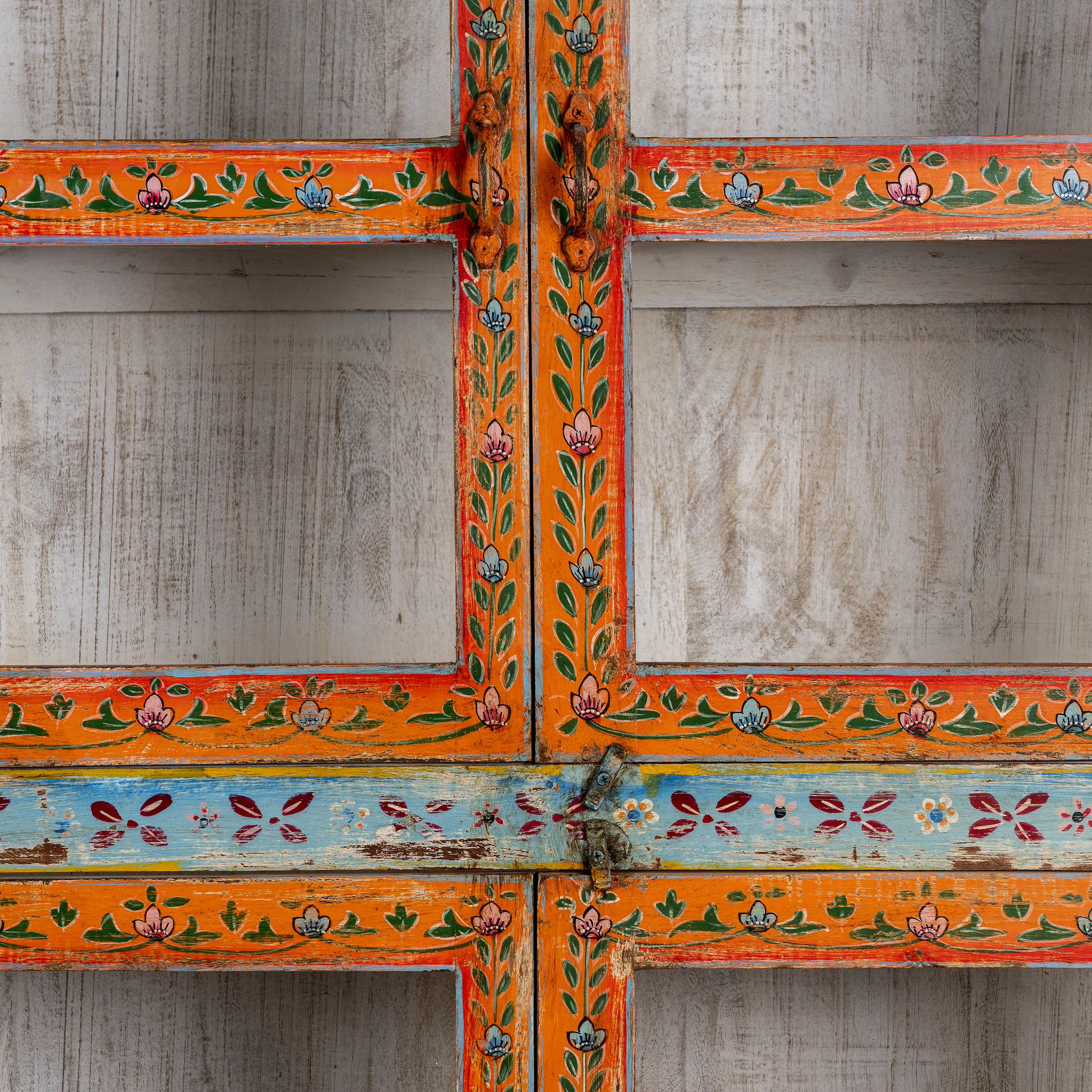 Close up image of a hand-painted reclaimed wood showcase cabinet with Ibiza-style motifs, glass-panelled doors, unique wooden furniture for living room, 213 × 40 × 170 cm.