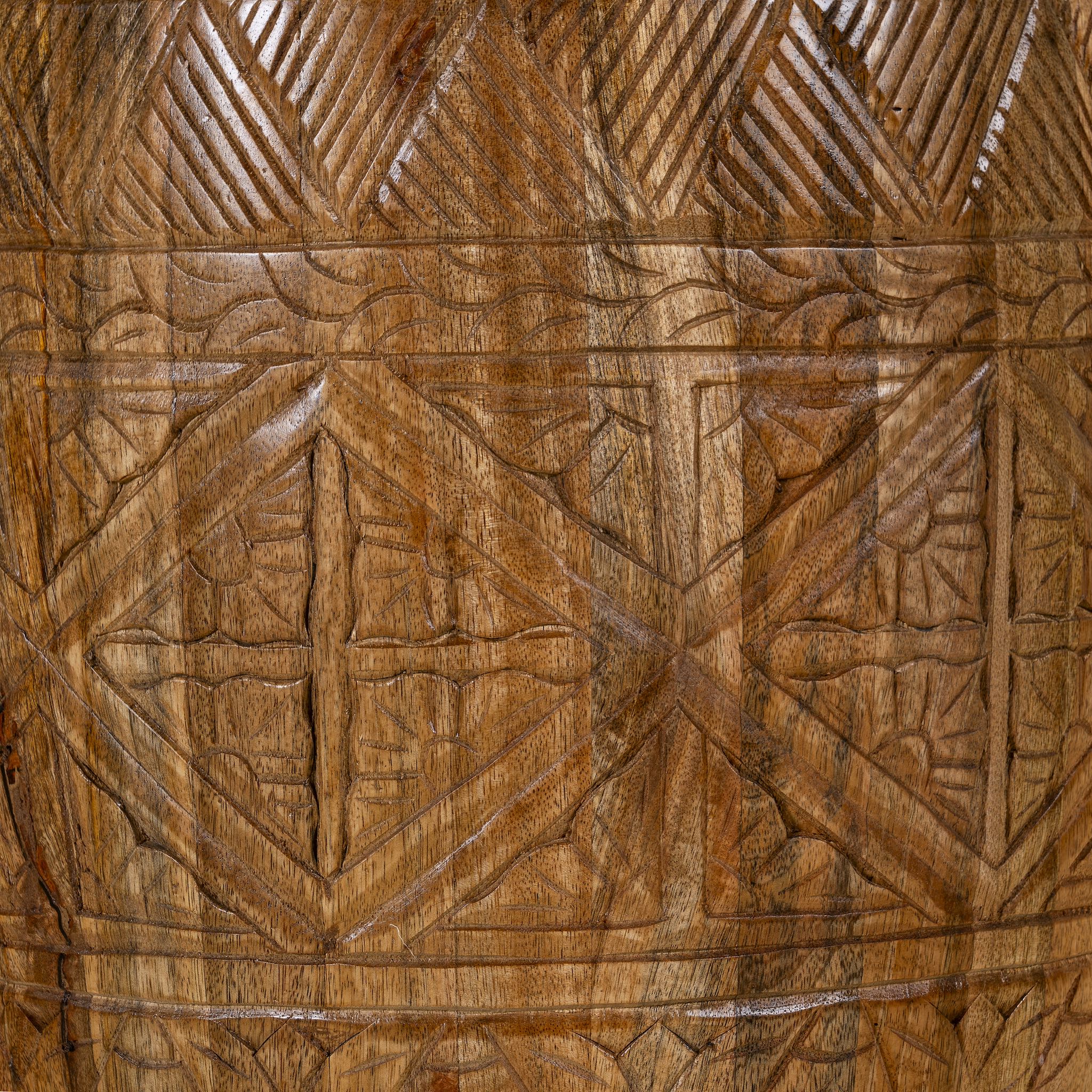 Close up picture of a round mango wood side table with hand carved floral and geometrical design.