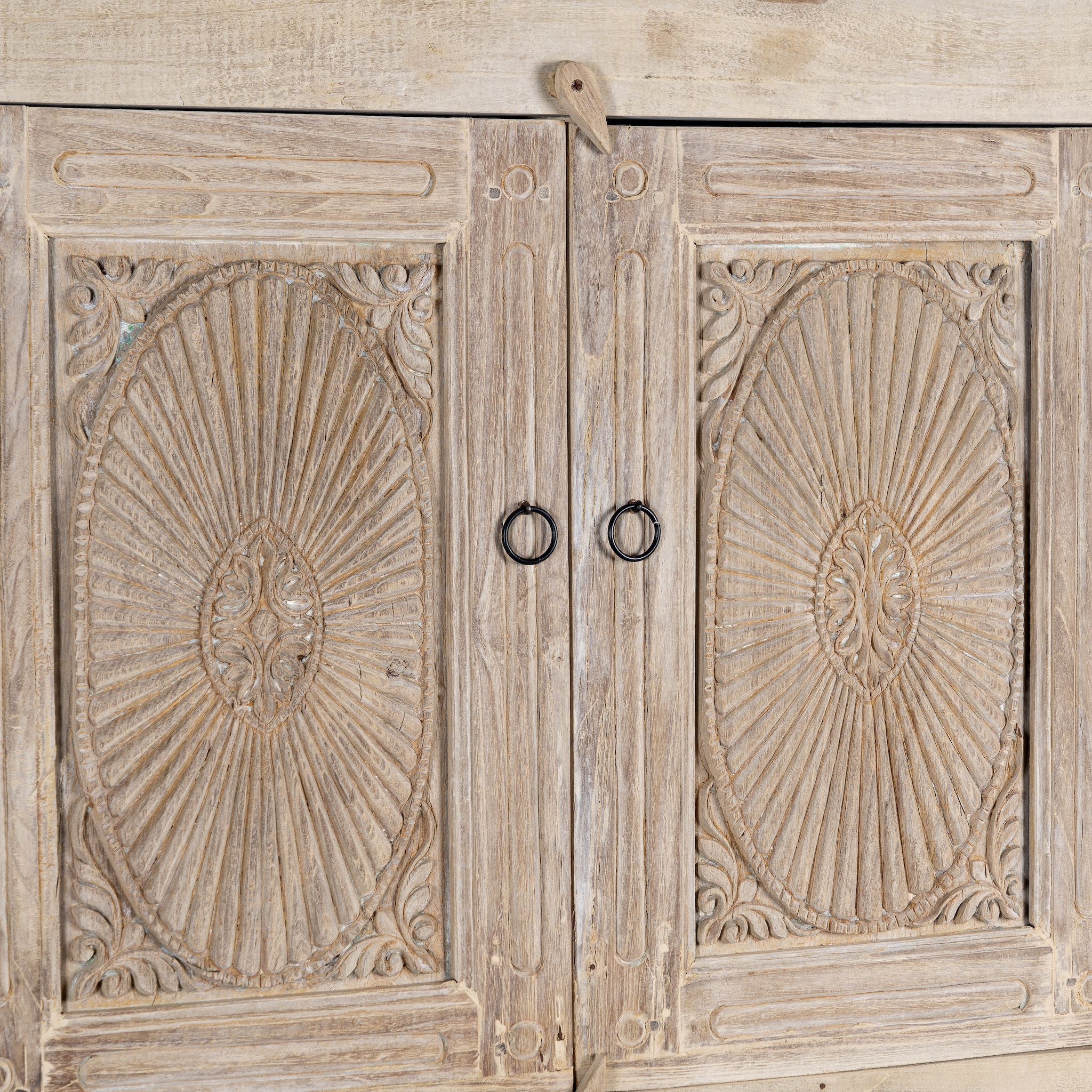 Close up picture of a handcrafted wooden carved wardrobe with antique panel doors – teak wood furniture with rustic charm and traditional detailing.