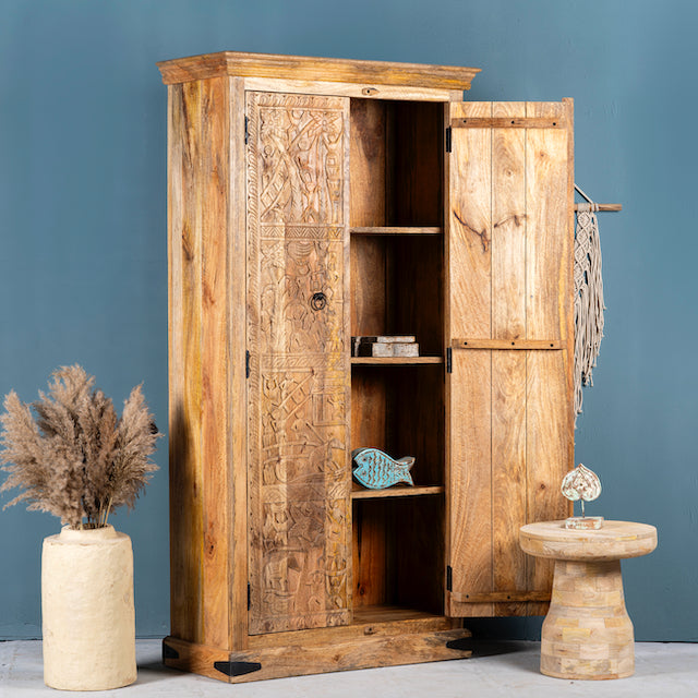 Side angle image with open doors of a hand-carved mango wood cabinet with traditional Indian village scenes – Rewalsar by Om Home & Garden, carved wooden furniture with cultural depth for bedroom interiors.