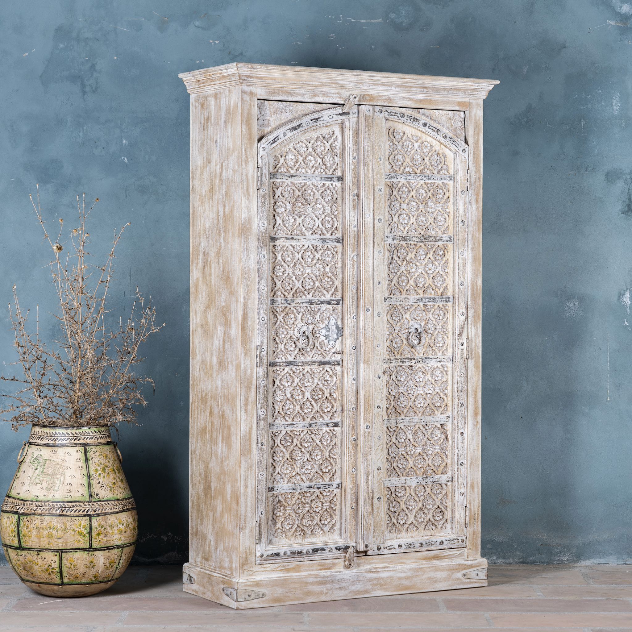 Side angle view of a cabinet made from an old teak door, featuring intricate hand-carved floral panels and a whitewashed finish — a striking piece with vintage charm and Ibiza style elegance.