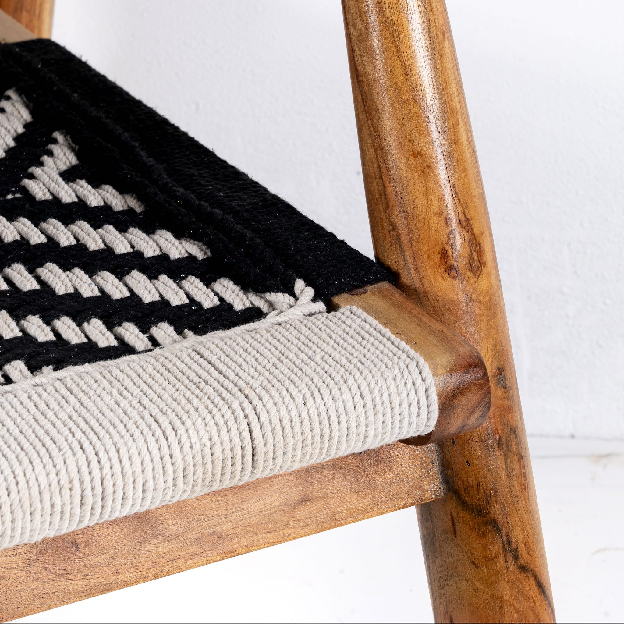 Close up image of a acacia wood chair with black-and-white handwoven cotton rope seat and backrest; artisanal wooden armchair, 61 × 47 × 83 cm.
