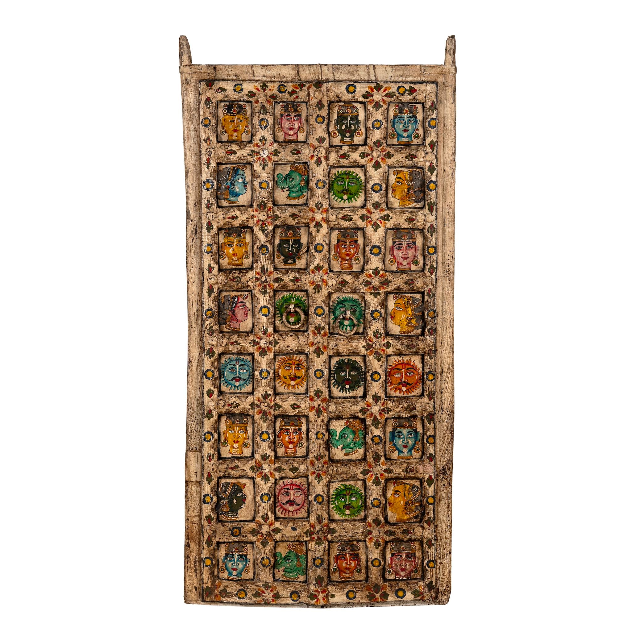 White background image of a tall vintage wall panel made from reclaimed teak wood, intricately hand-painted with a grid of vibrant deity faces, animals, and symbolic motifs in rich colors, each framed within carved squares, reflecting traditional Indian folk art.