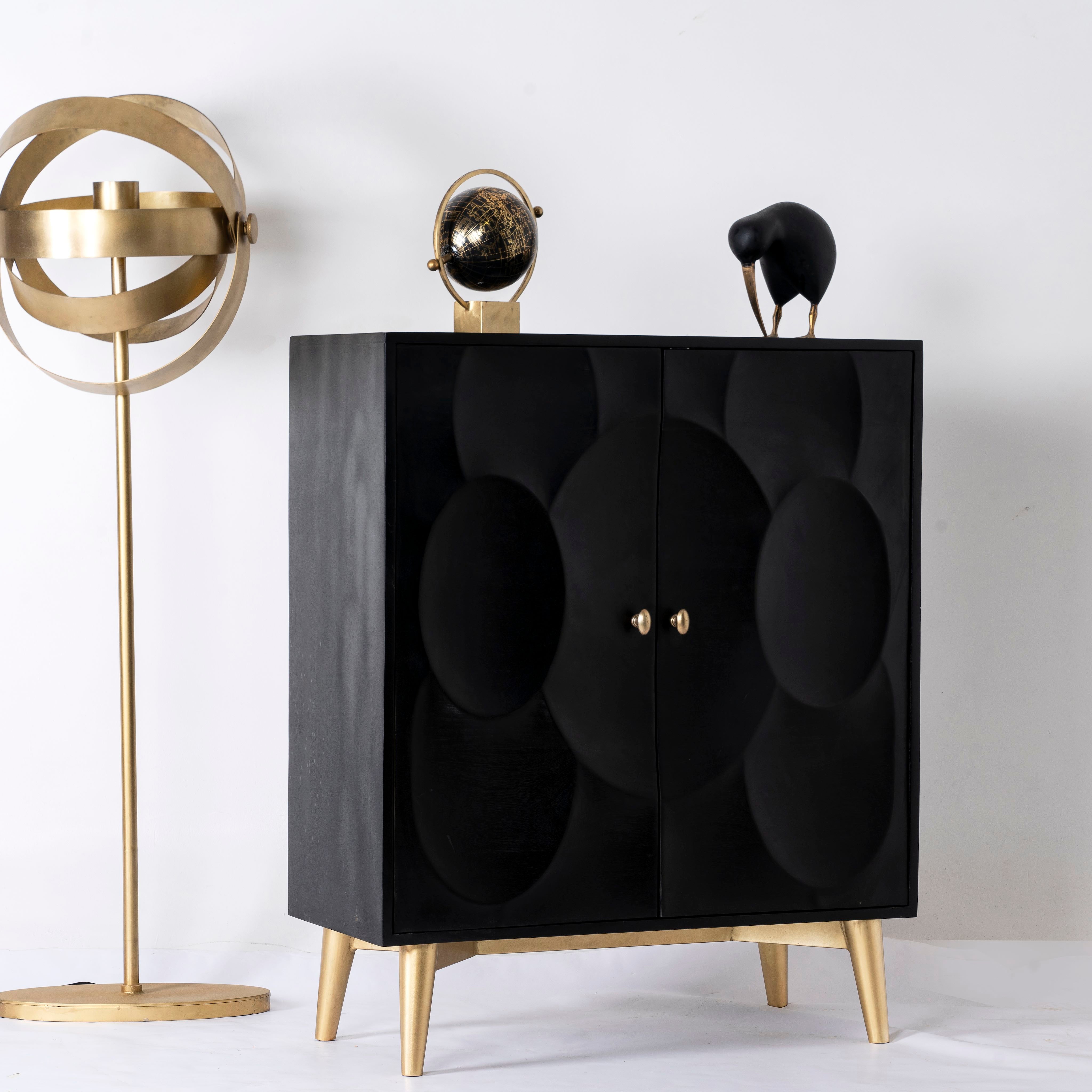 Side angle image of a lack mango wood cabinet with carved circular patterns and brass-plated iron base, 91 × 43 × 111 cm.