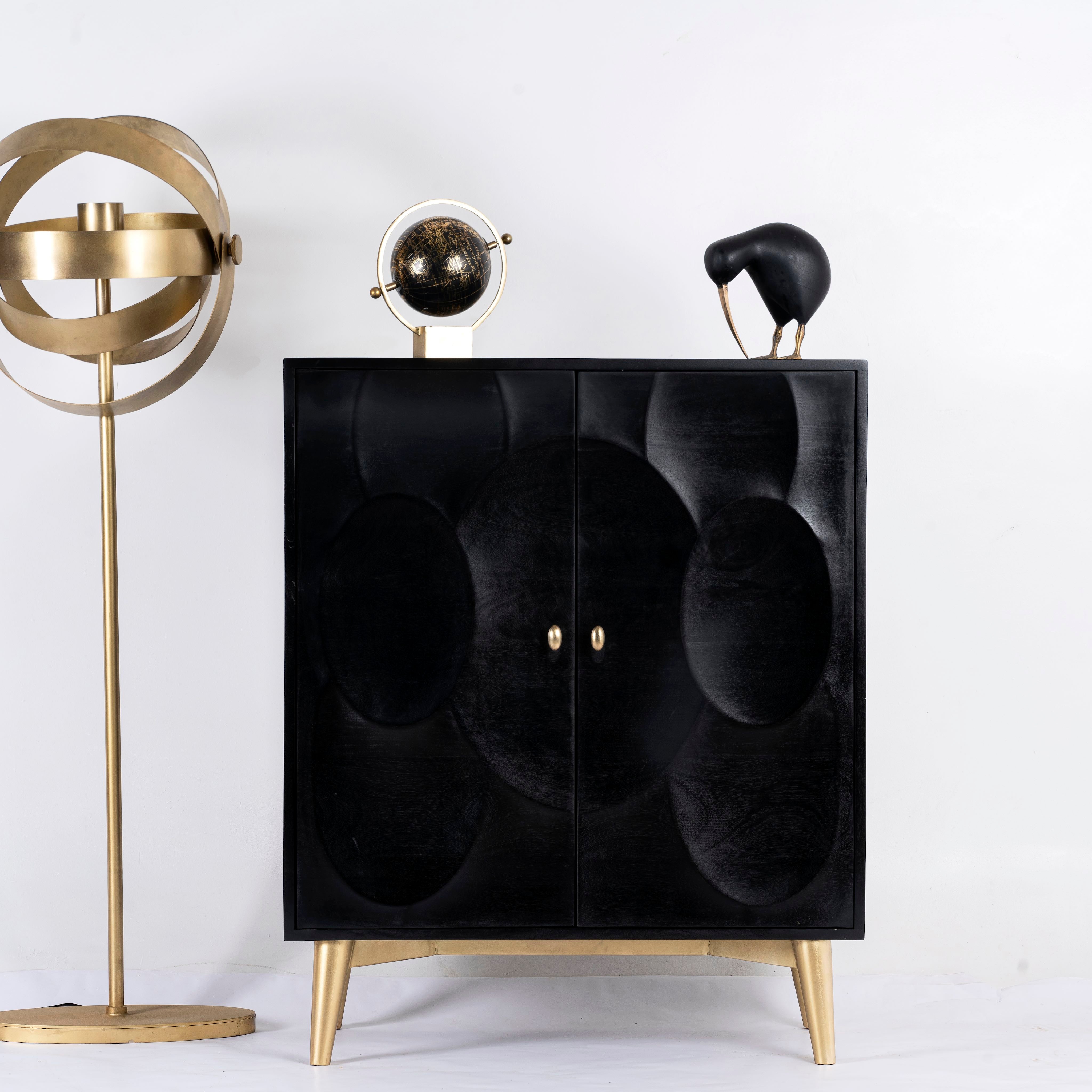 Black mango wood cabinet with carved circular patterns and brass-plated iron base, 91 × 43 × 111 cm.